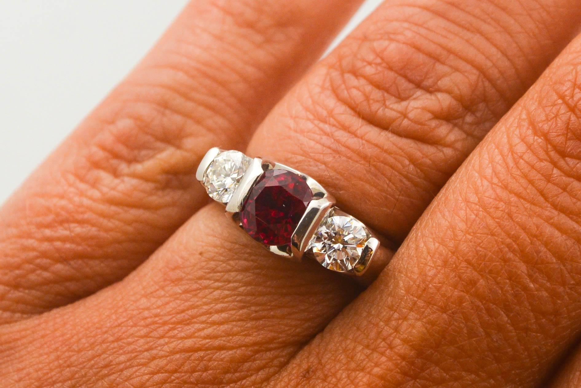 An intense red Thailand Ruby is the centerpiece of this three stone ring. Two dazzling round brilliant cut diamonds (0.66 ctw F-G color, VVS2 internal clarity) adorn the sides of this tasteful ring. Crafted in high polish platinum and currently a