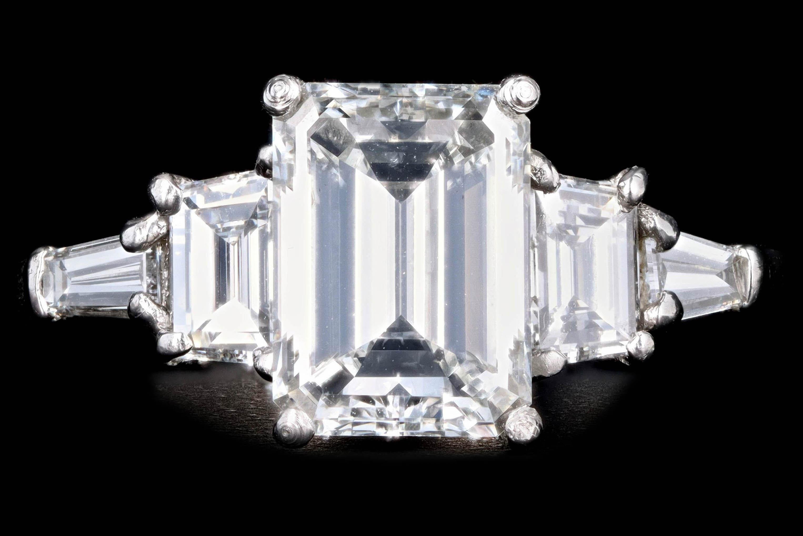 Era: Modern

Composition: Platinum 

Primary Stone: Emerald Cut Diamond

Carat Weight: 2.03 Carats

Color/Clarity: H / VS2

Accent Stone: Trapezoid & Tapered Baguette Cut Diamonds

Carat Weight: .75 Carats Total

Color/Clarity: G-H / VS1-2

Total