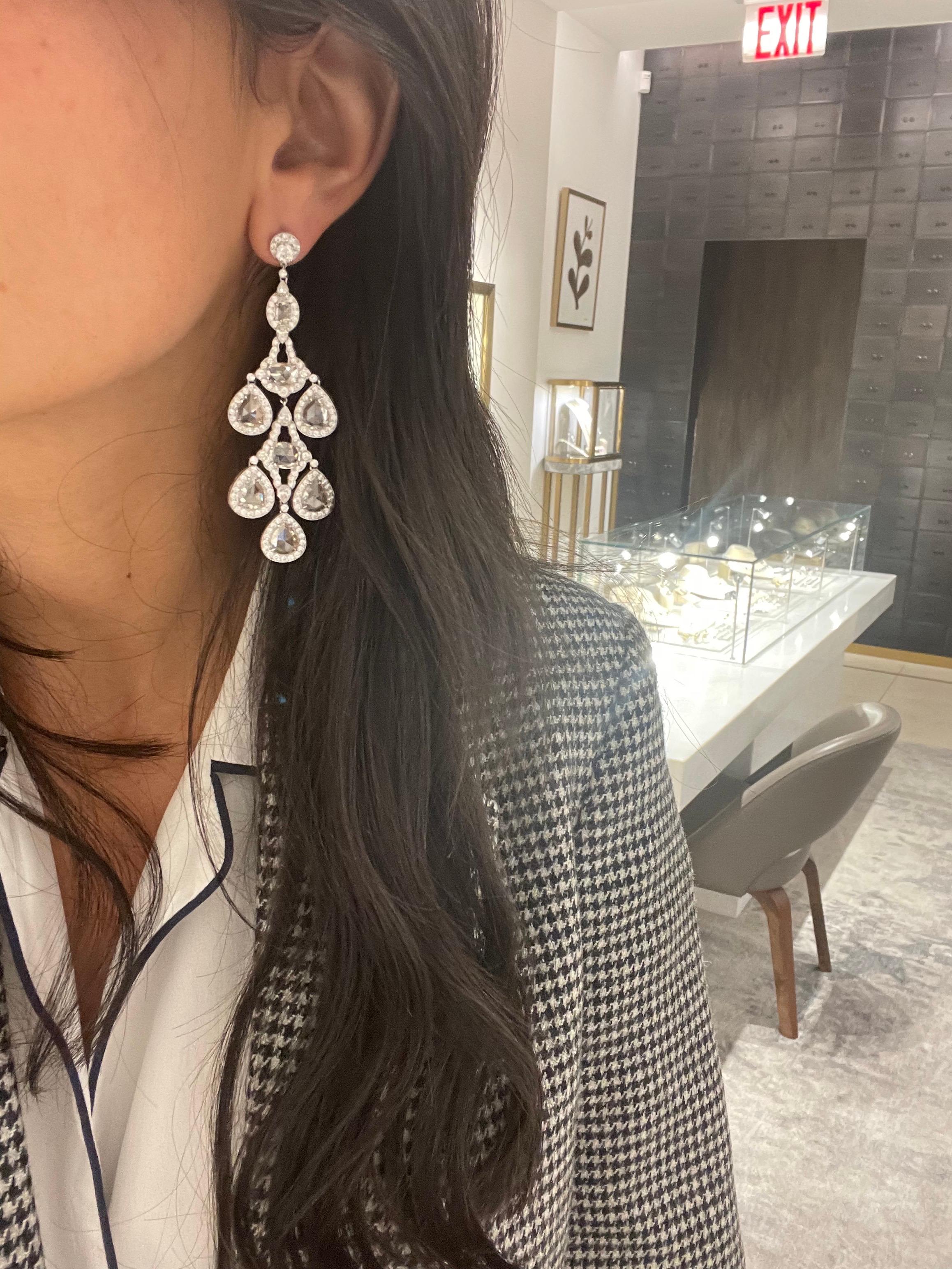 These dramatic hanging chandelier style earrings showcase rose-cut oval and pear shaped diamond centers surrounded by round micro pave diamond settings. Round brilliant diamonds are bezel set on top. 
Set in platinum with post backs. The earrings