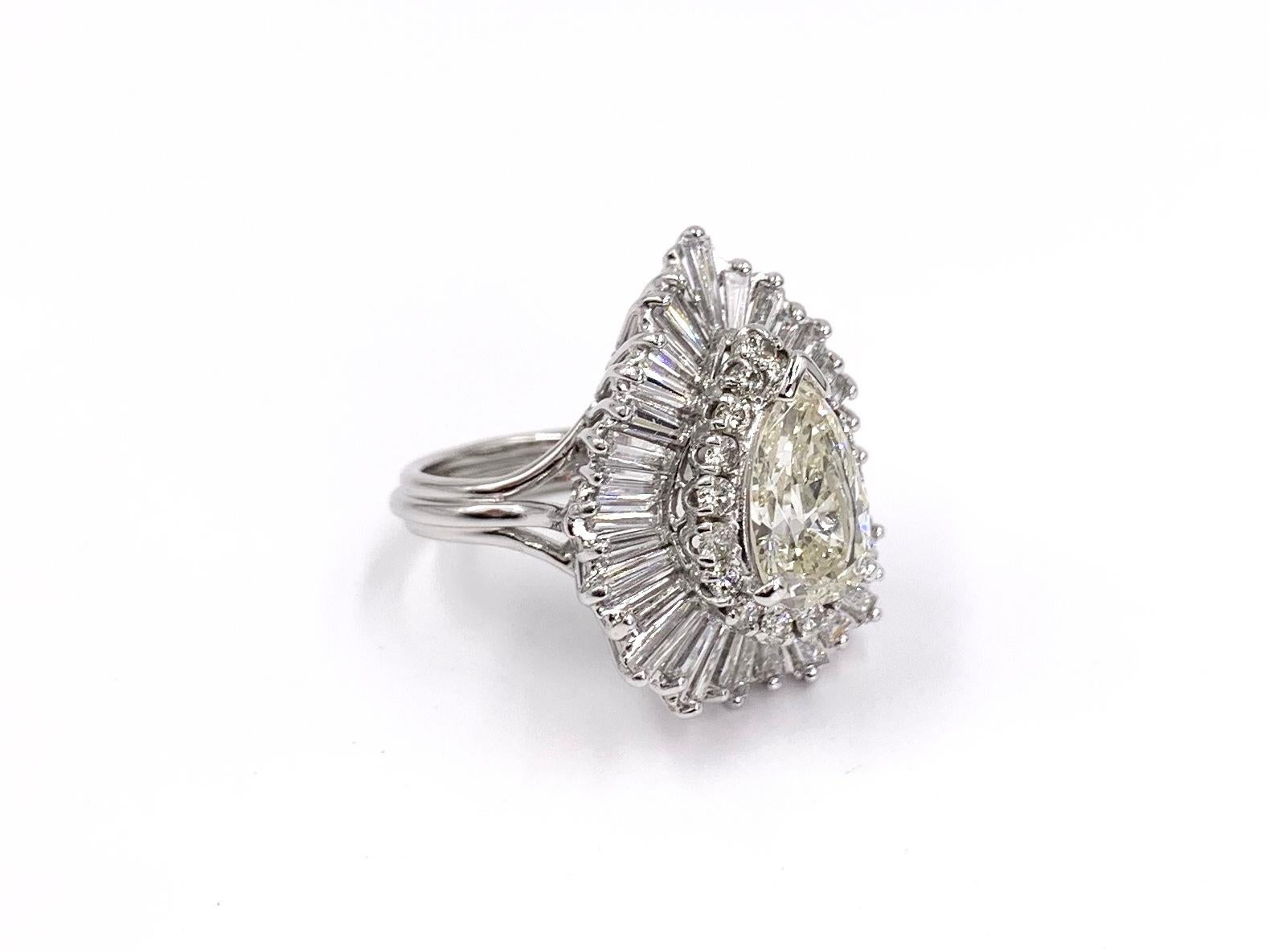 A beautiful 2.07 carat pear shape diamond is perfectly surrounded by a halo of round brilliant diamonds and further adorned with baguette diamonds arranged in a classic ballerina design. Center diamond has been evaluated to be an approximate K