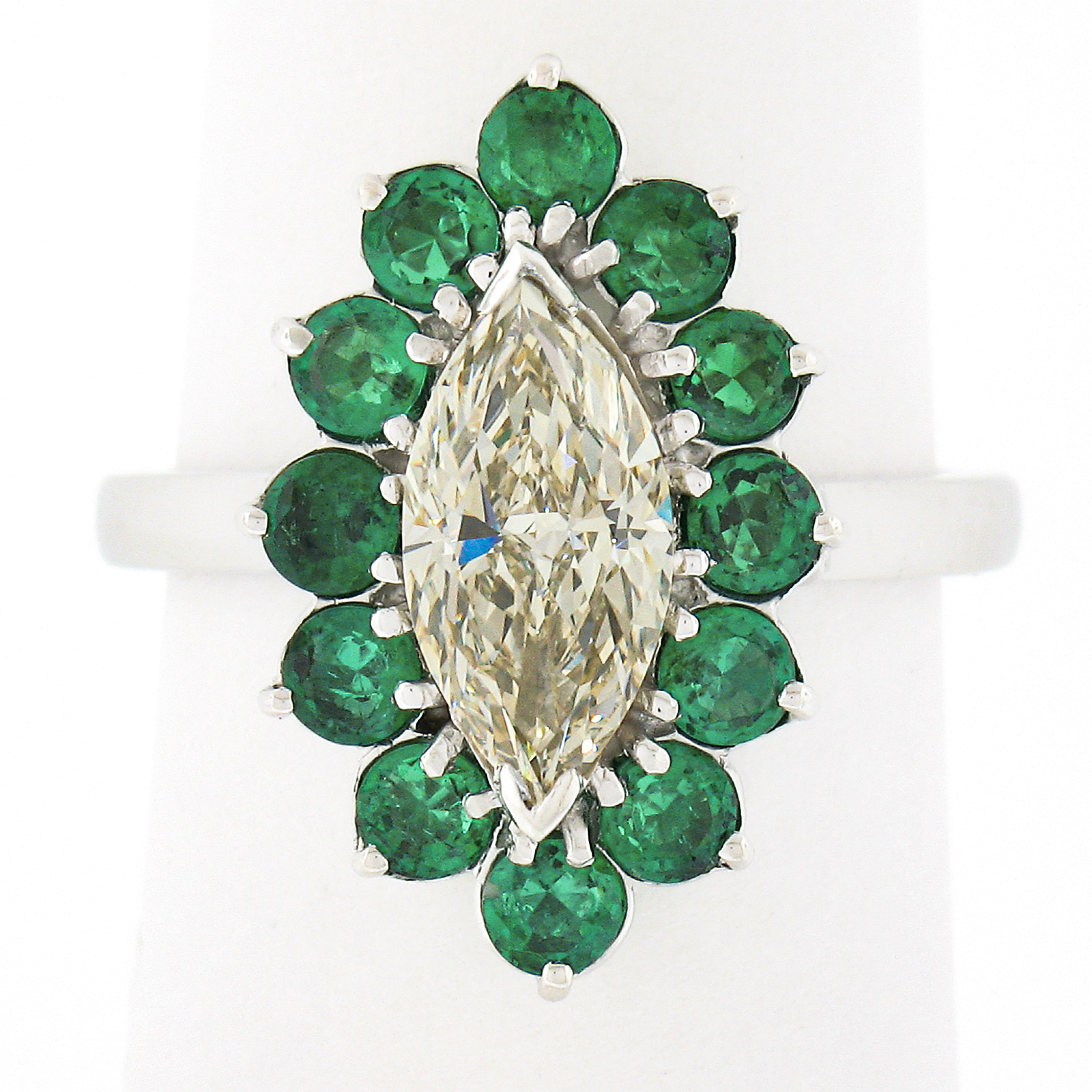 You are looking at a truly breathtaking diamond and emerald ring that is crafted in solid platinum. It features a stunning, marquise cut, light yellow diamond neatly prong set at the center and displays a lovely and warm light yellow color and