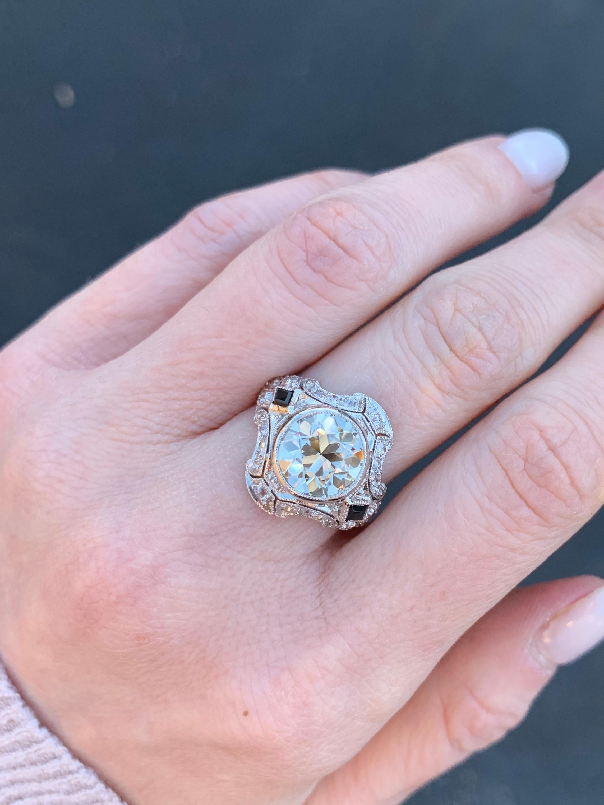 Circa 1950’s, this vintage platinum shield style ring is heavily Edwardian-era influenced featuring a lively 2.40 carat round brilliant GIA certified diamond center. Ring is accented with 2 rhombus cut sapphires and further adorned with 24