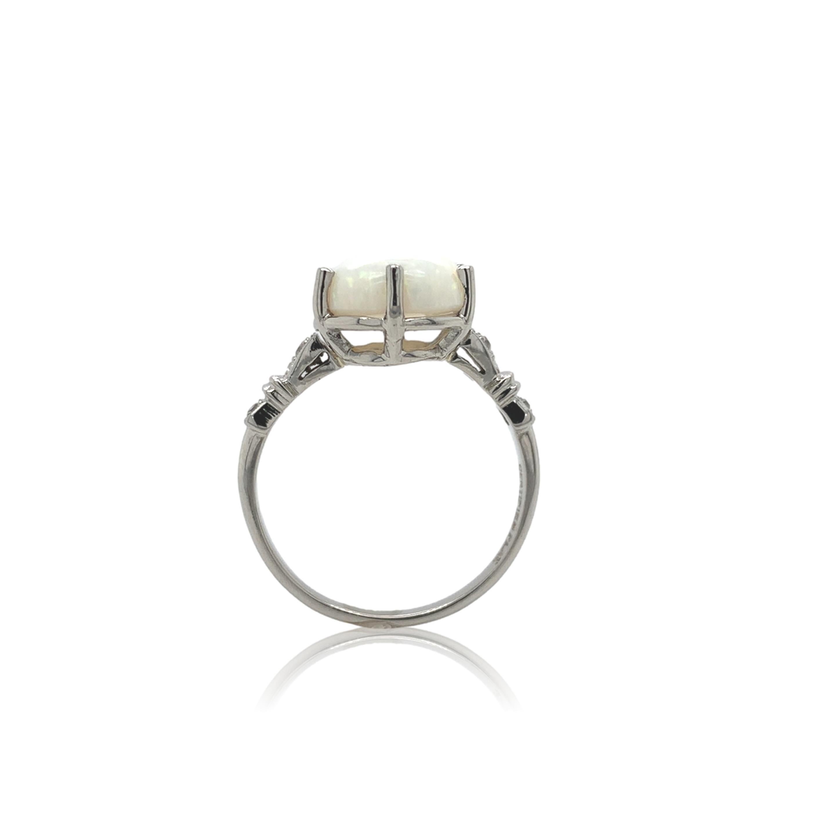 Antique platinum ring featuring a natural Australian opal weighing 2.80 carats. The opal has a white body color with lots of red-pink play of color. The oval cabochon opal measures about 12.5mm x 9.5mm. The ring fits a size 7.75 finger and weighs