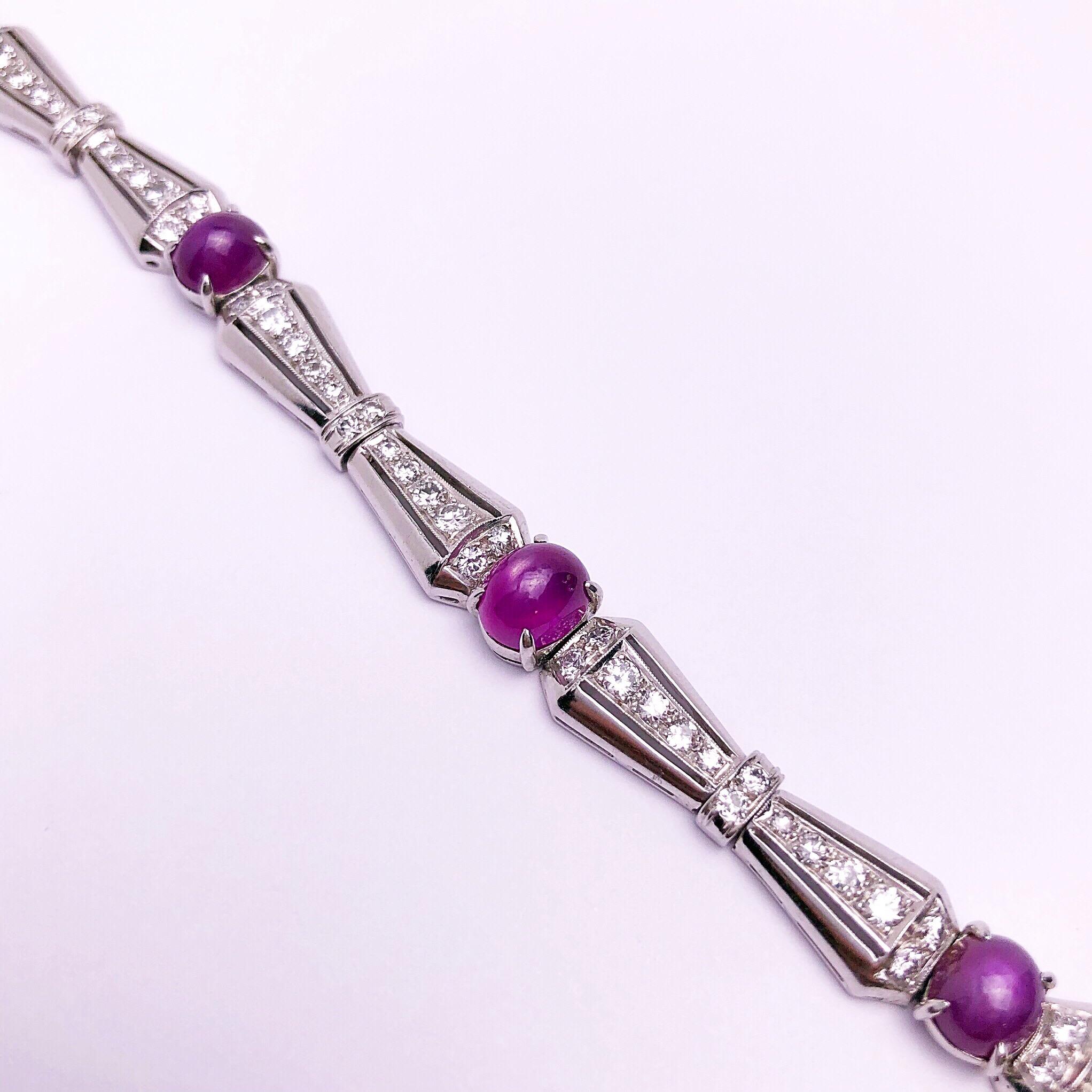 Ce bracelet magnifique et unique présente 5 rubis étoilés cabochons de forme ovale et environ 2,00 carats de diamants blancs dans une monture d'inspiration art déco.  
Le fermoir est estampillé PLAT et possède une chaîne de sécurité pour plus de