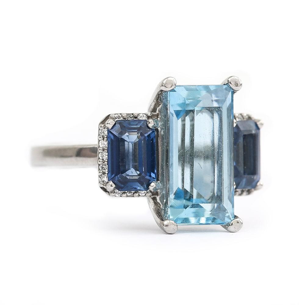 A striking contemporary bespoke platinum aquamarine, sapphire and diamond three stone trilogy ring. The emerald cut centre aquamarine is est. 3.20cts, with two lovely matched emerald cut sapphires est. at 0.70cts each. Making a total of 1.40cts of