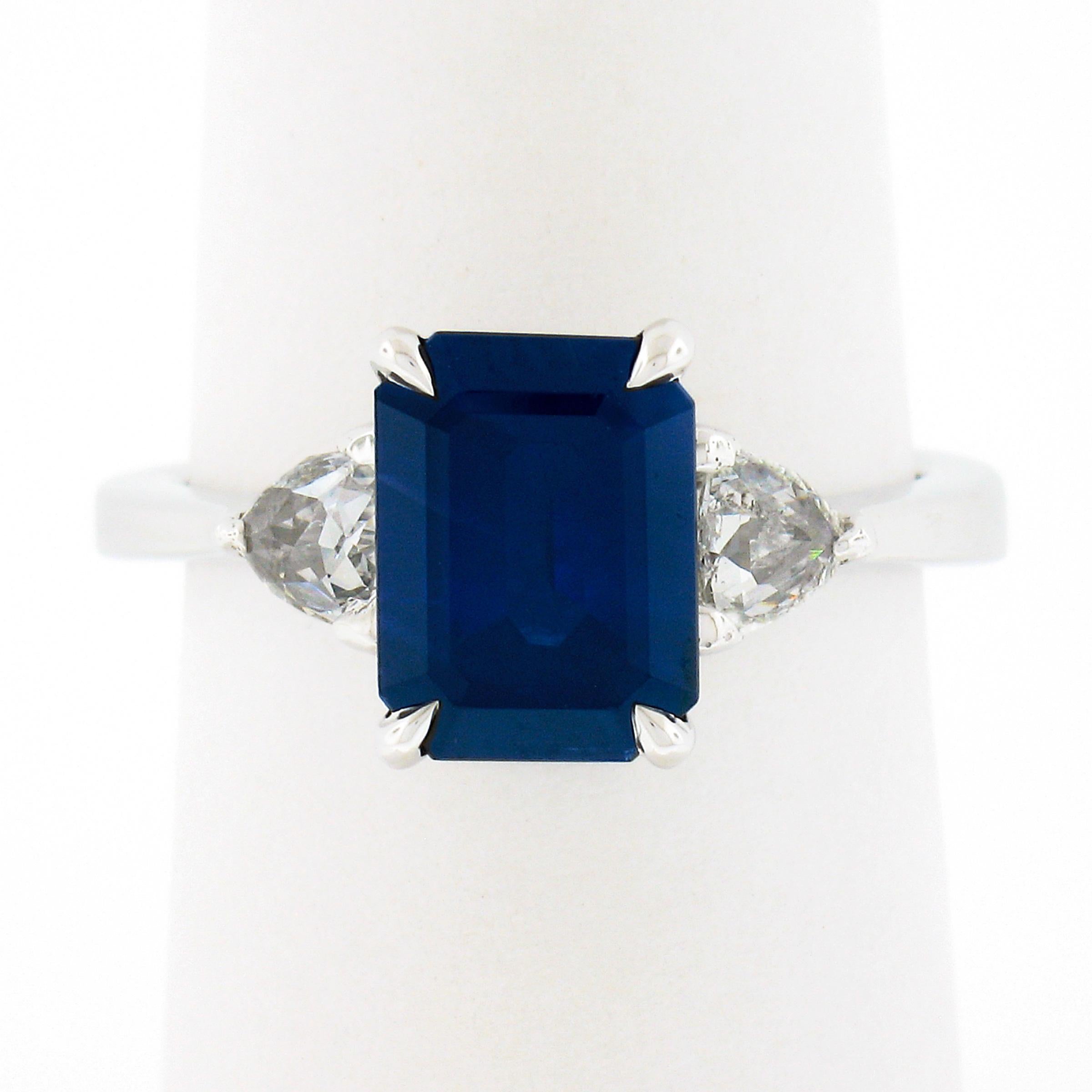 This breathtaking and classically styled sapphire and diamond engagement ring is crafted in solid platinum and features a magnificent, Gubelin certified, emerald cut sapphire solitaire that's perfectly prong set at the center and flanked on either