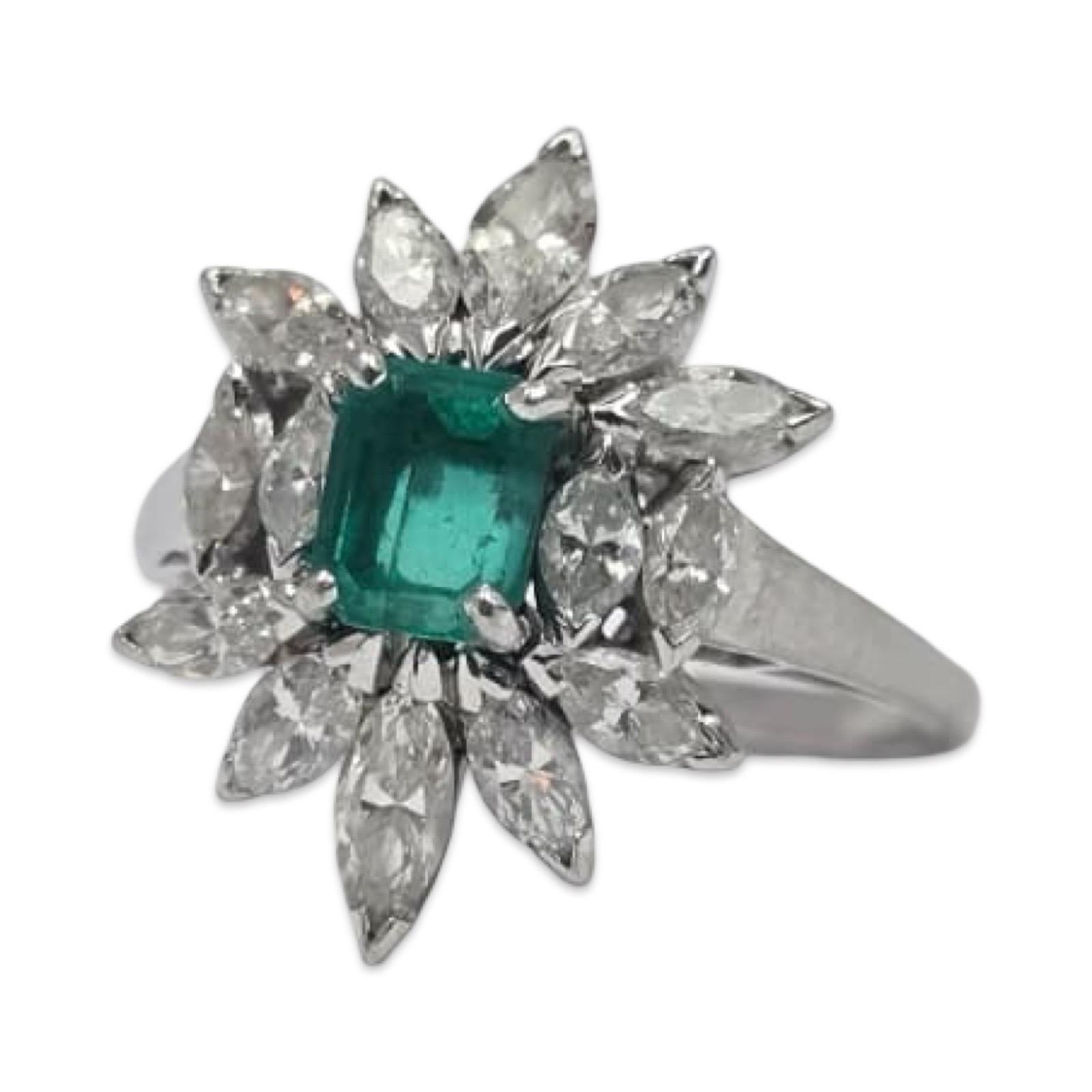 Ein exquisiter Blumenring aus Platin, in dessen Zentrum ein heller Smaragd im Smaragdschliff mit einem Gewicht von etwa 0,90 Karat steht, umgeben von zwölf Diamanten im Marquiseschliff mit einem Gesamtgewicht von etwa 2,74 Karat. Die Diamanten sind