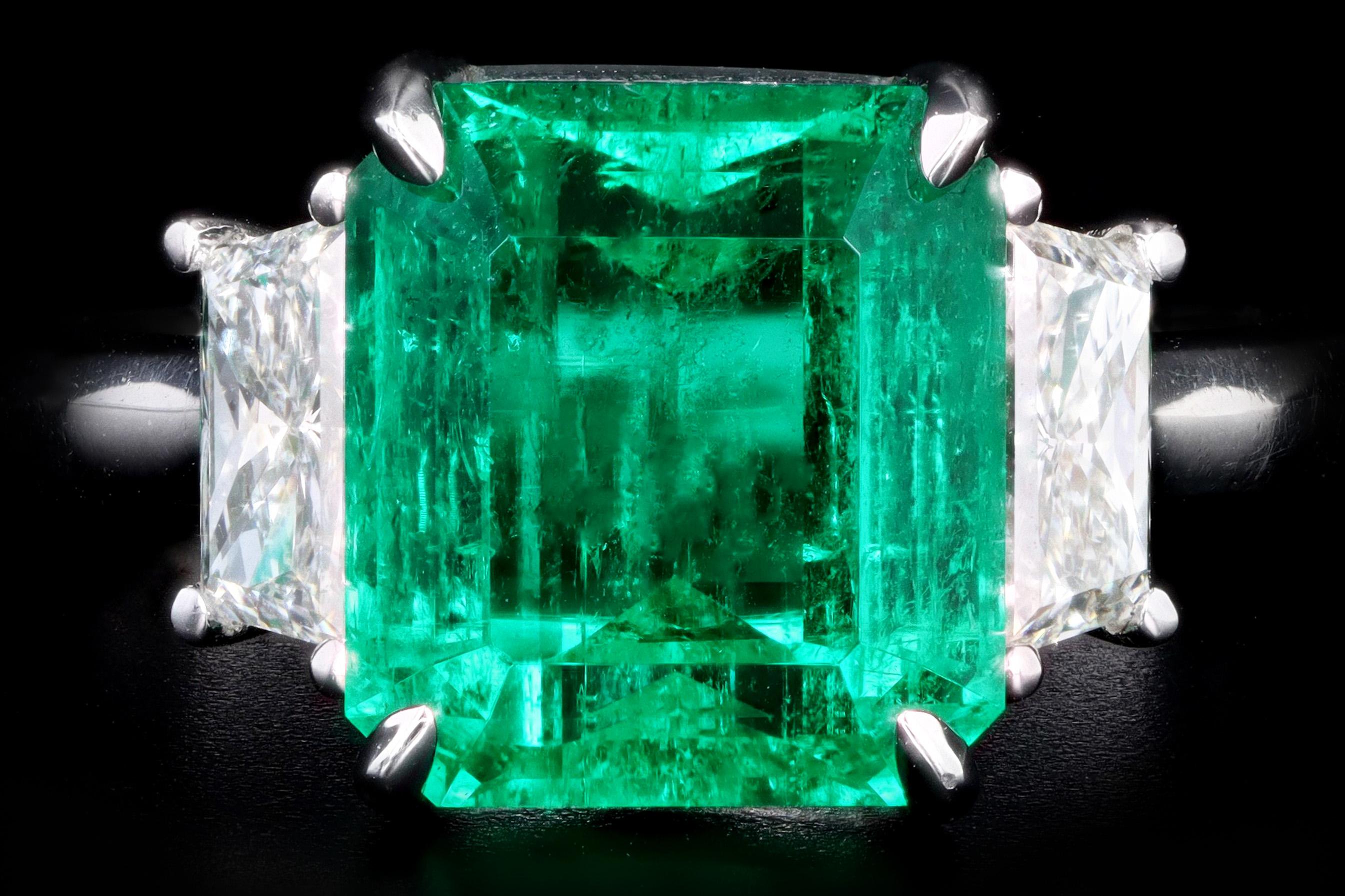 Era: Modern

Composition: Platinum 

Primary Stone: Emerald Cut Natural Emerald 

Origin: Colombia

Treatment: Clarity(Minor) 

Carat Weight: Approximately 4.26 Carats

Accent Stone: 2 Trapezoid Cut Diamonds

Carat Weight: Approximately .75 Carats