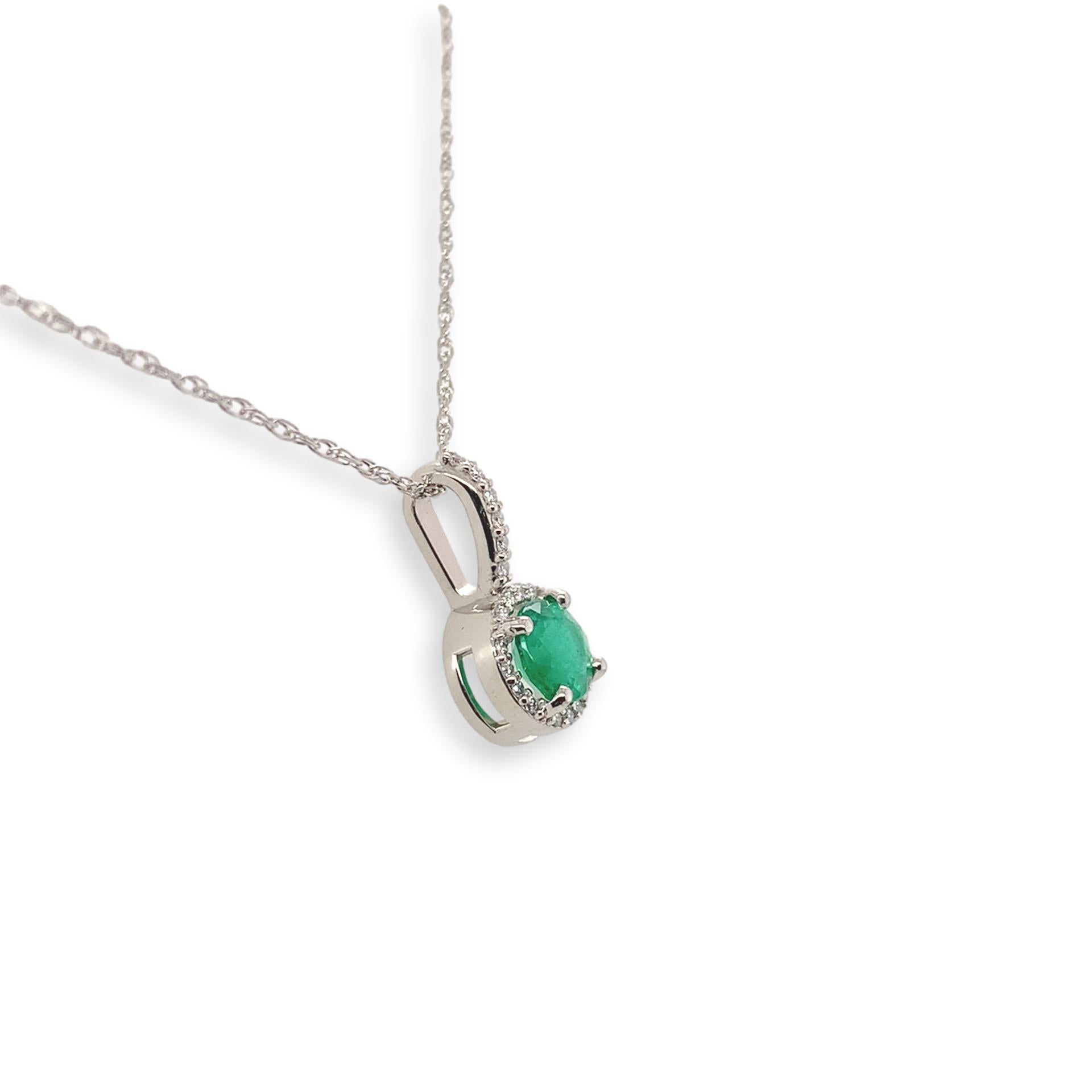 Pendentif en platine avec émeraude véritable extraite de la terre et halo de diamants. L'émeraude de taille ronde mesure environ 5,3 mm et présente une couleur moyennement foncée et une clarté fine. L'émeraude pèse 0,55 carat. Il y a 22 minuscules