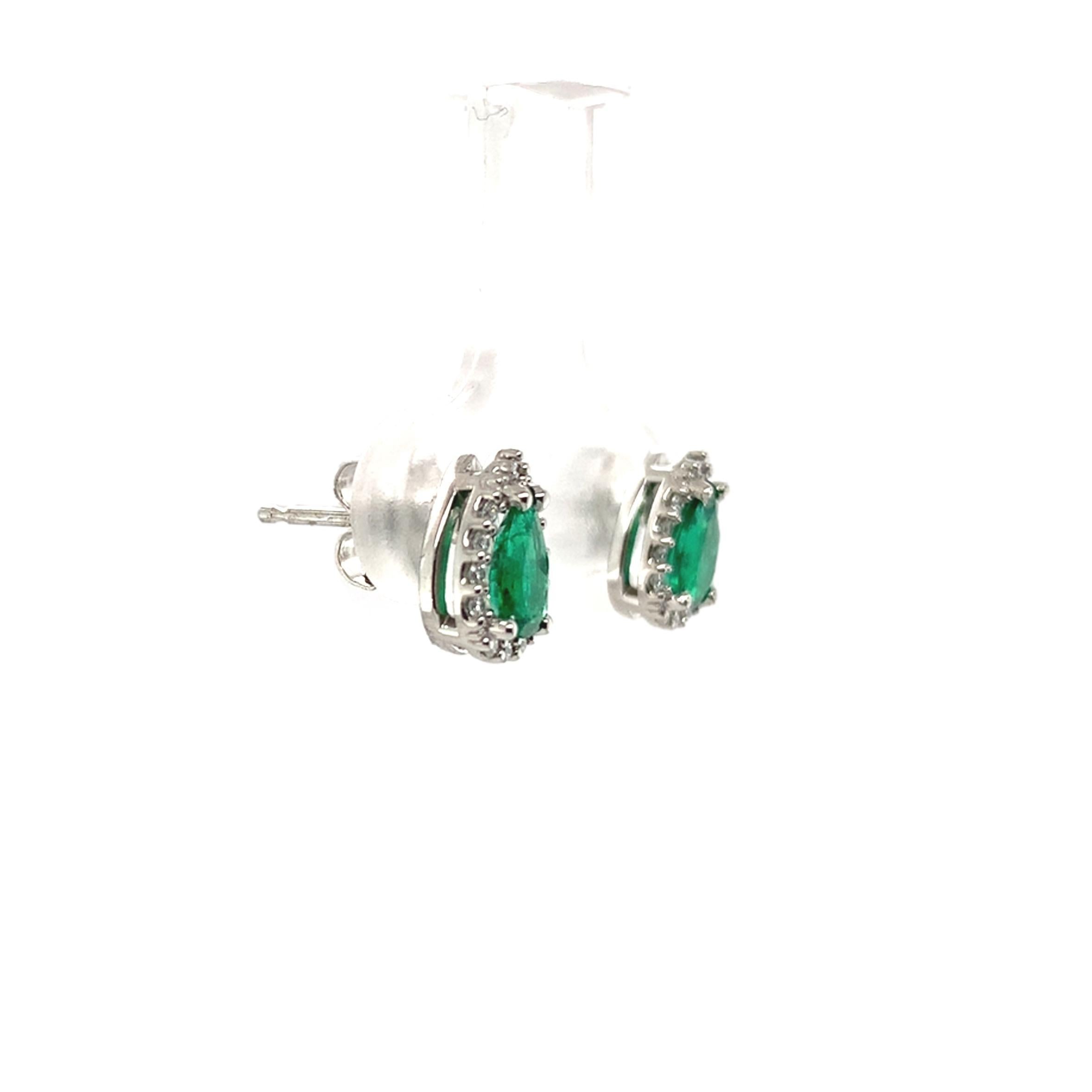 A pair of platinum genuine earth mined emerald stud earrings with diamond halos. The pear cut emeralds measure about 6mm x 4mm and have medium dark color and fine clarity. The emeralds weigh .60 carats total. There are 24 tiny round diamond accents