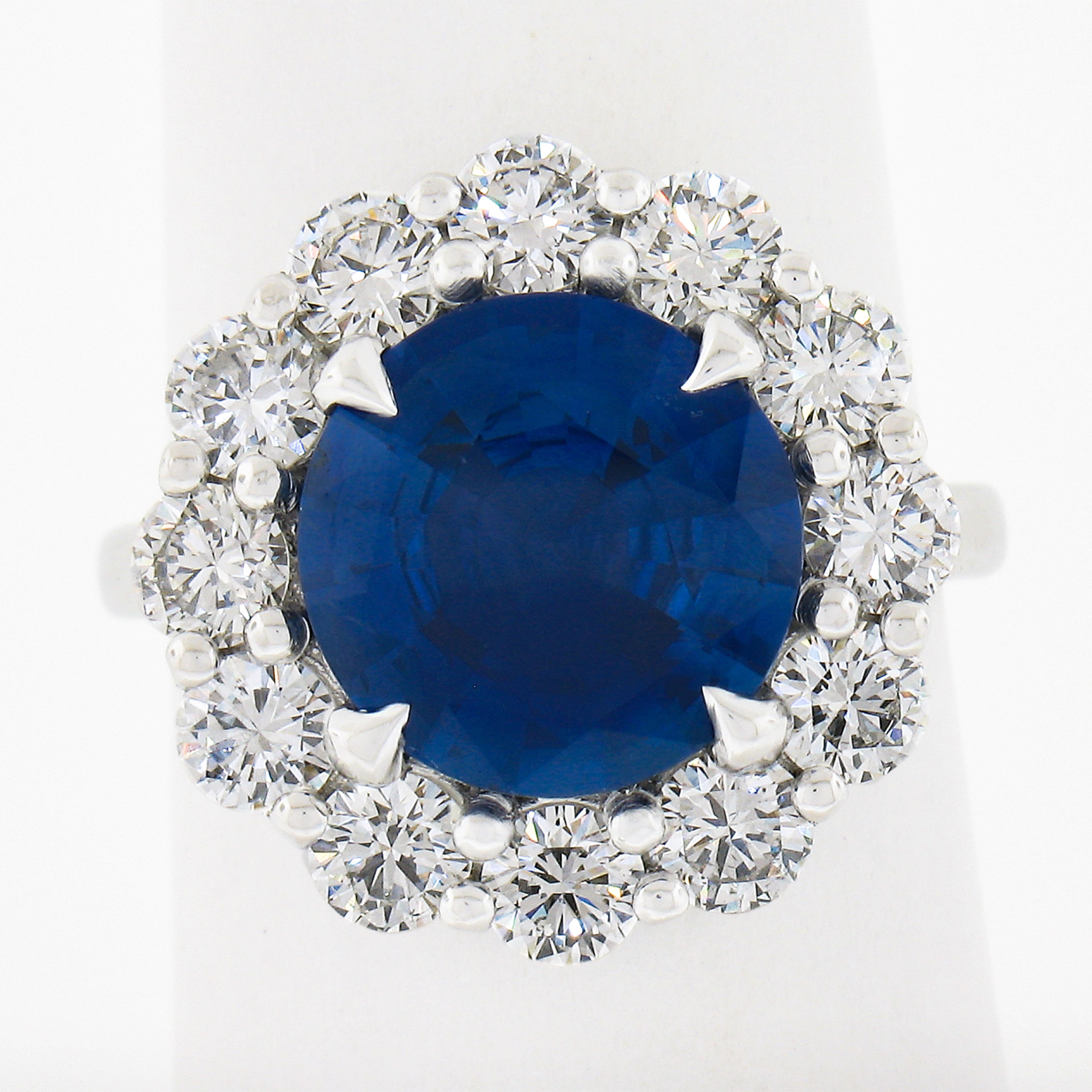 This jaw dropping statement ring is crafted in solid platinum and features a gorgeous, GIA certified, round brilliant cut sapphire set at the center of a magnificent diamond halo. The large sapphire weighs 4.55 carats and is a beautiful, super