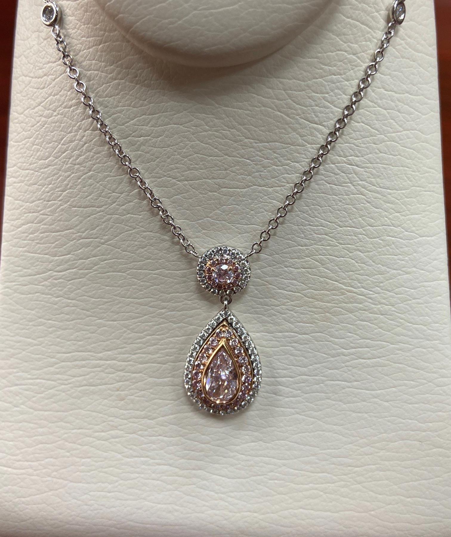 This stunning pendant is cast in platinum and accented with 18 karat rose gold. The featured center diamond is a .68 carat fancy light pink pear shaped diamond surrounded with round fancy light pink and brilliant colorless diamonds.  The connected