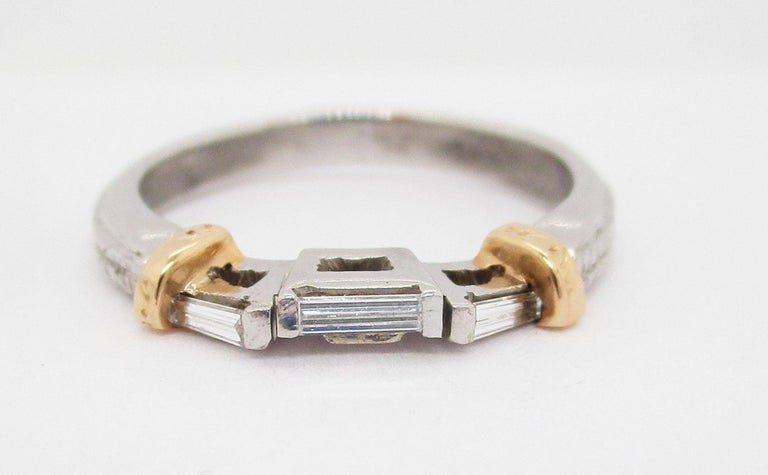 This gorgeous wedding band is platinum and 18k yellow gold and boasts a lovely three stone horizontal baguette layout. The white gold shoulders of the ring have a finely textured detailing that makes this ring unique! The shoulders are accented by