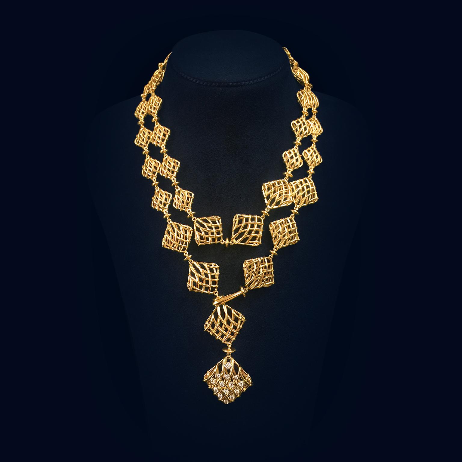 Intricate openwork cushions give this necklace depth and distinction. 18k yellow gold wires cross over in a basket weave to form cushion shapes that circulate in a repeated pattern of large to small. In between each cushion is a round disk. A swan