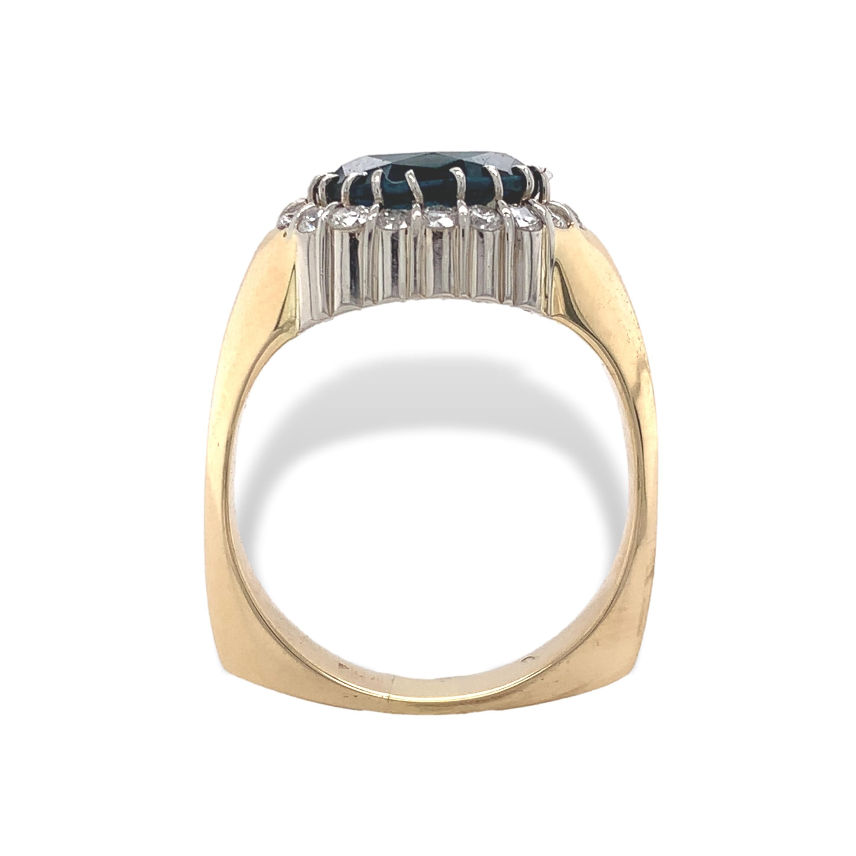 Platinum and 18K yellow gold blue topaz and diamond ring. The oval deep teal blue topaz measures about 9mm x 7mm. The squared Euro shank is 18K gold and the top is platinum. There are 18 round brilliant cut diamonds measuring about 1.7mm and