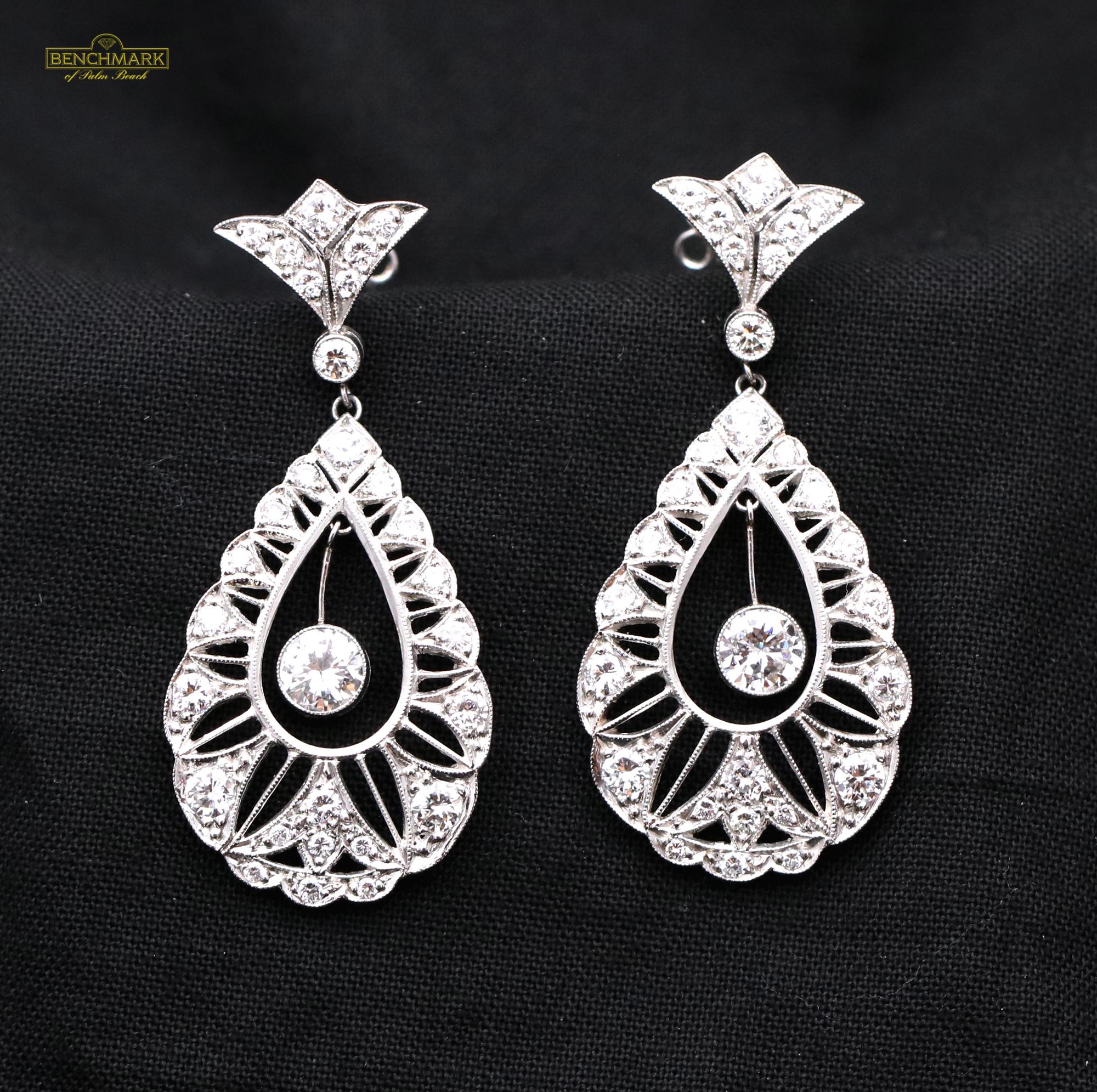 A pair of platinum antique reproduction earrings, in the Belle Epoque style centered around a bezel set round brilliant cut diamond weighing approximately 0.66ct. The center stone is suspended in the center of the earring via a platinum bar, it is