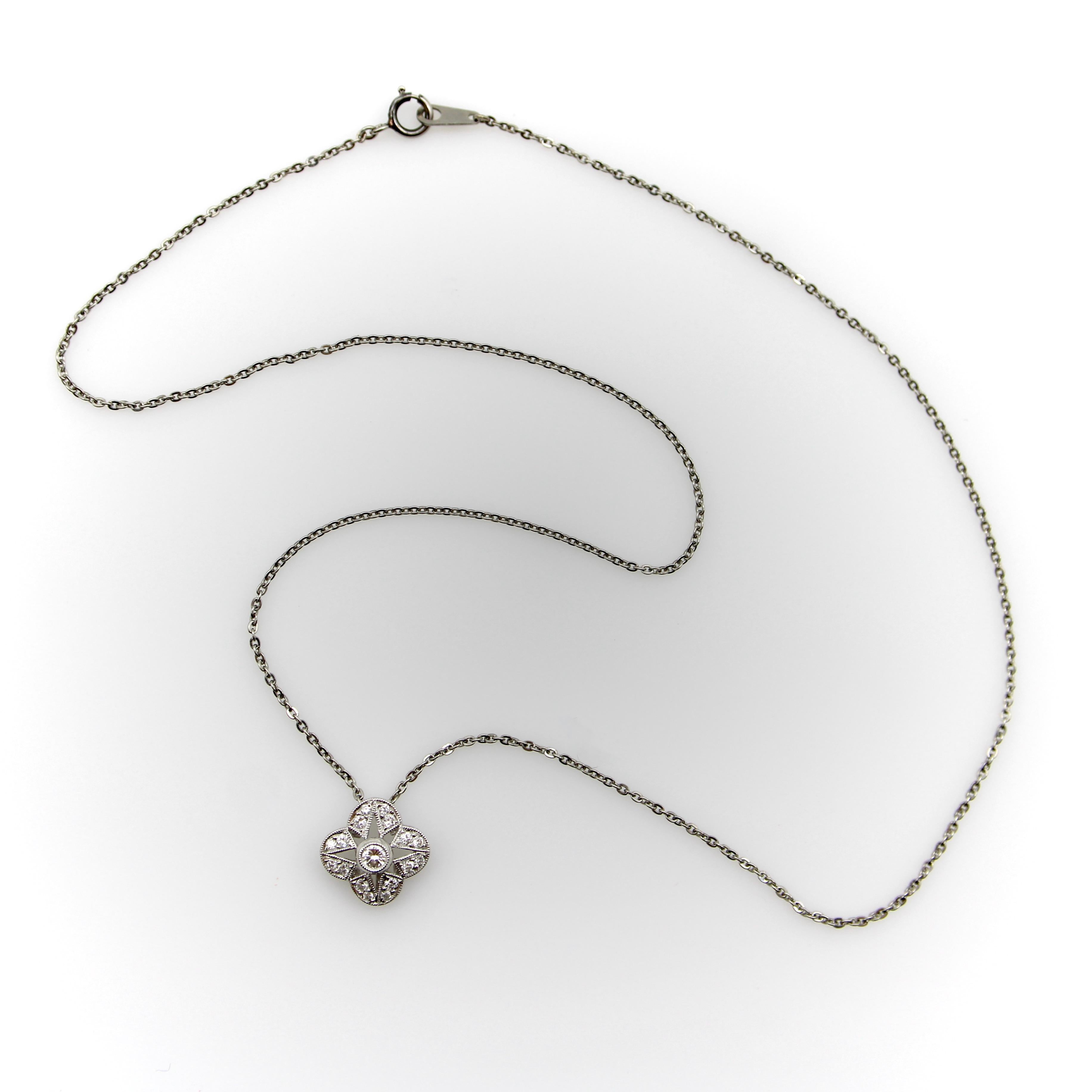This beautiful platinum necklace features a quatrefoil shaped pendant full of sparkling diamonds. A round brilliant diamond adorns the center of the pedant, while sixteen smaller diamonds are bezel set into the surrounding surface of the pendant.