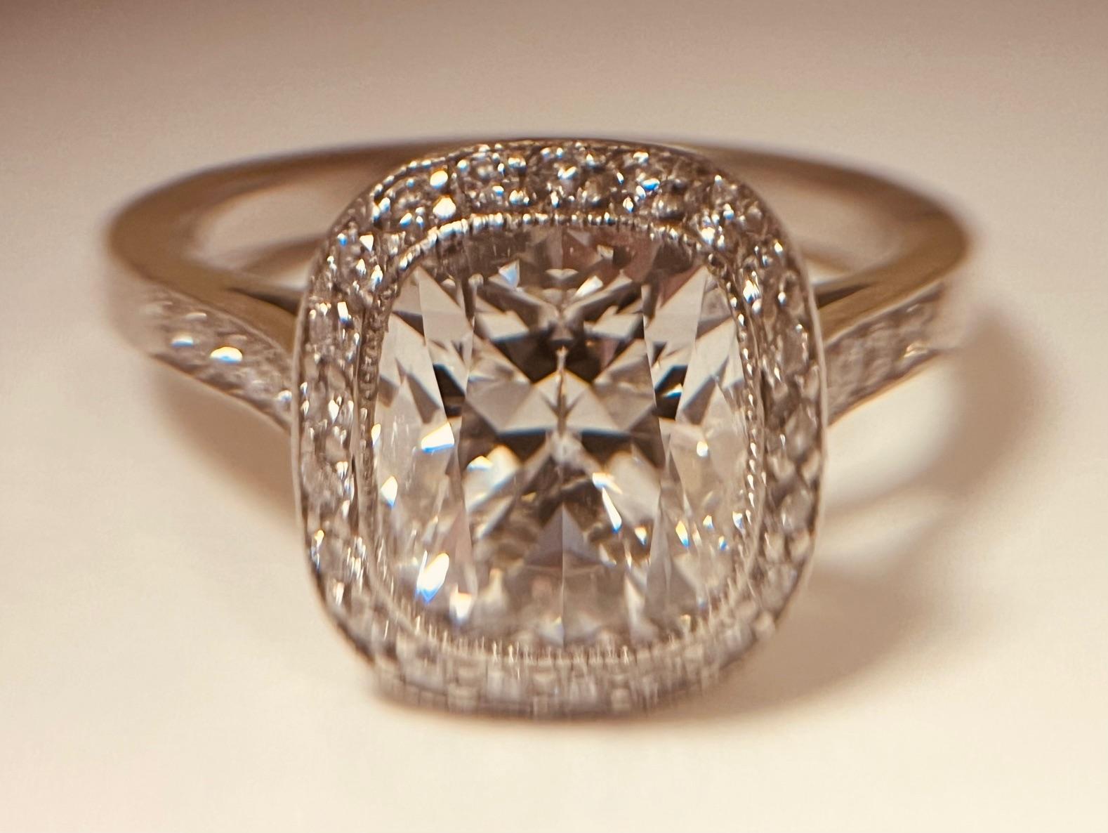 Bague de halo en platine et diamant solitaire. Le diamant principal de taille coussin, certifié par le GIA, pèse 2,15 carats et est de couleur F et de pureté SI1. Il est entouré de diamants ronds de taille brillant et d'épaules serties de la même