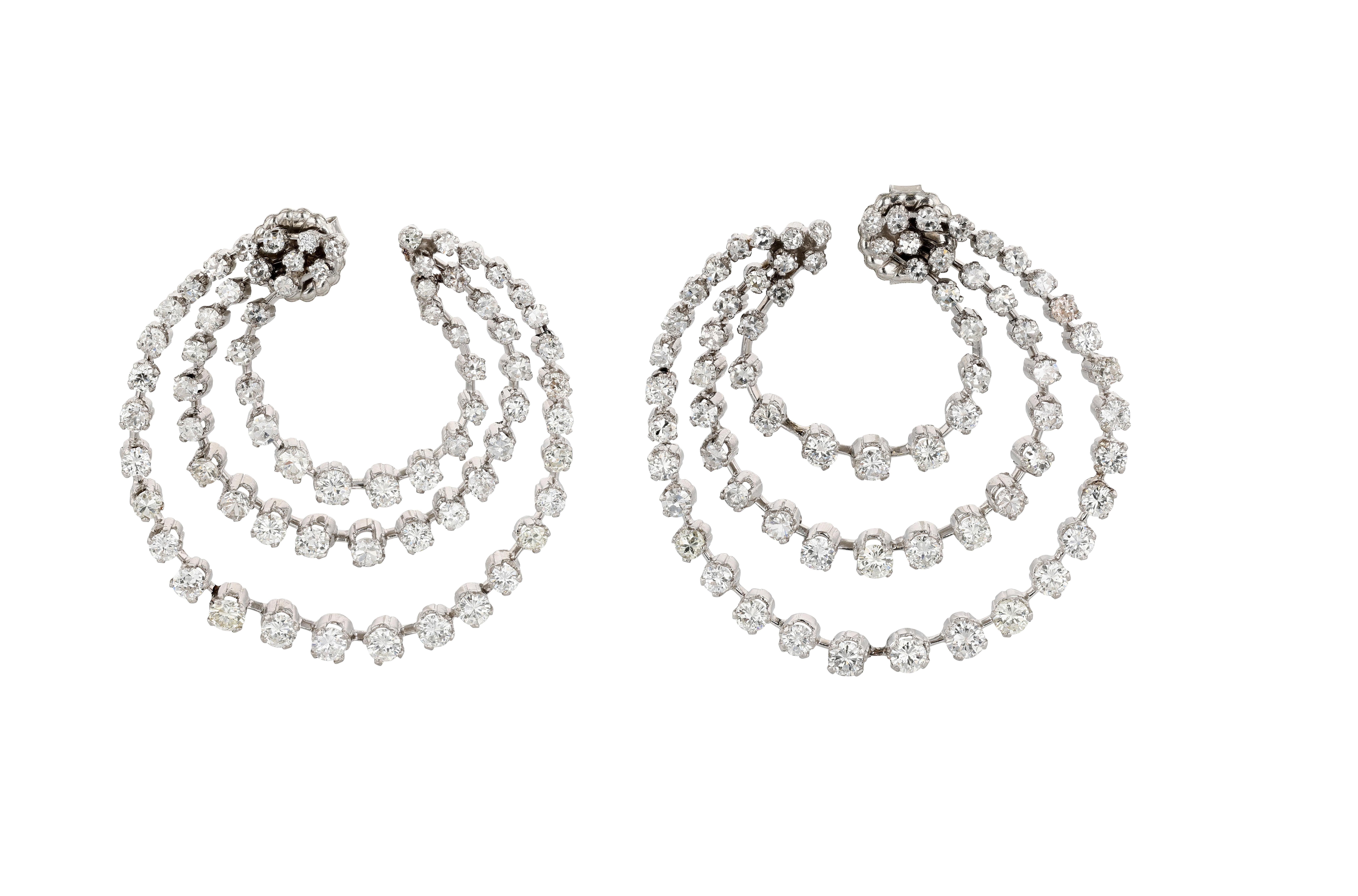 A pair of unique and visually interesting platinum and diamond earrings each designed as a series of three rings becoming gradually larger in size. Each ring features stations, each station set with an old European cut diamond. Each of the three