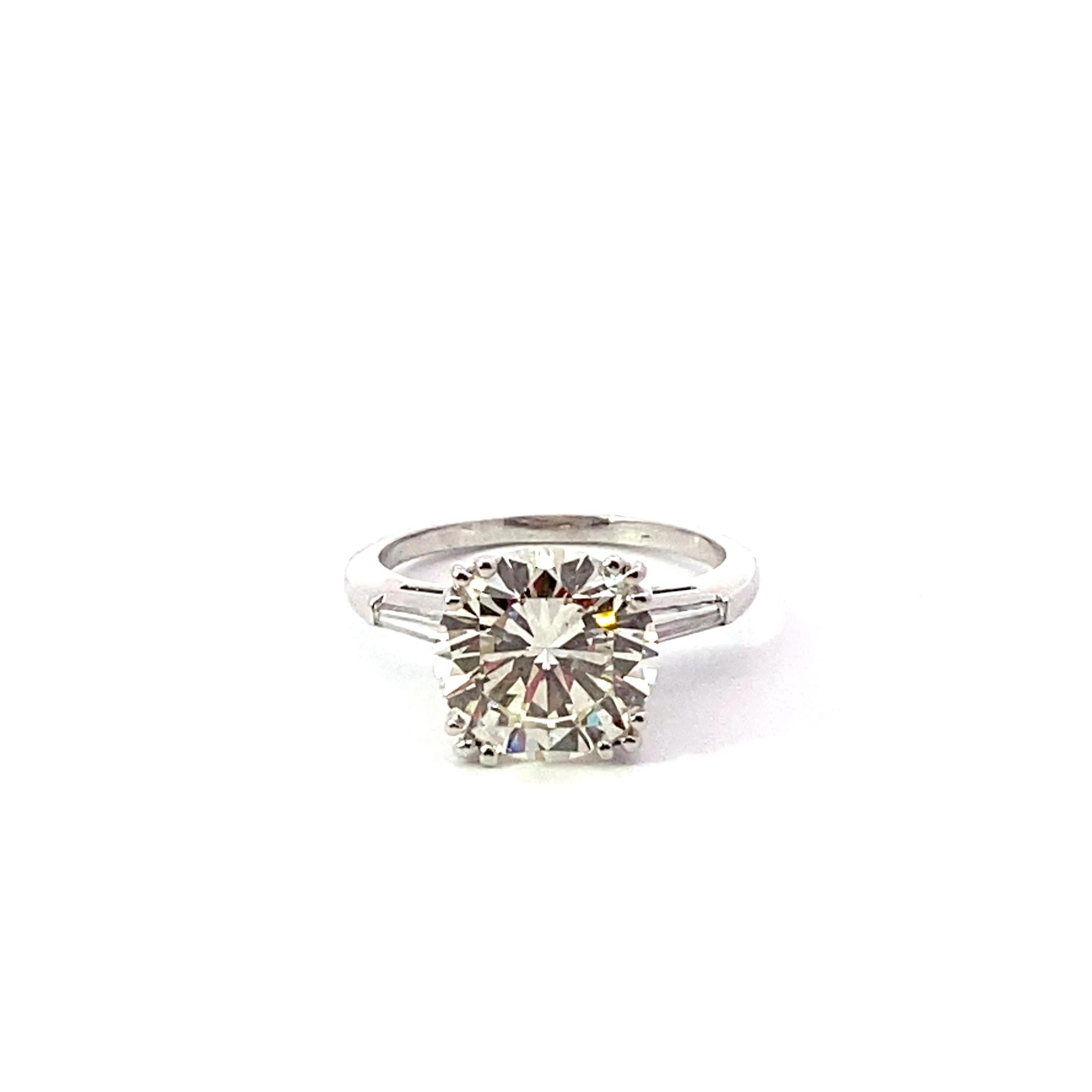 Bague en platine contenant un diamant rond brillant de 4,23 carats. Serti de 2 diamants baguettes trafiqués. 
La bague pèse environ 6,20 grammes.   
La pierre centrale pèse 4,23 carats, de couleur L et de pureté SI1.
Il y a 2 diamants de taille