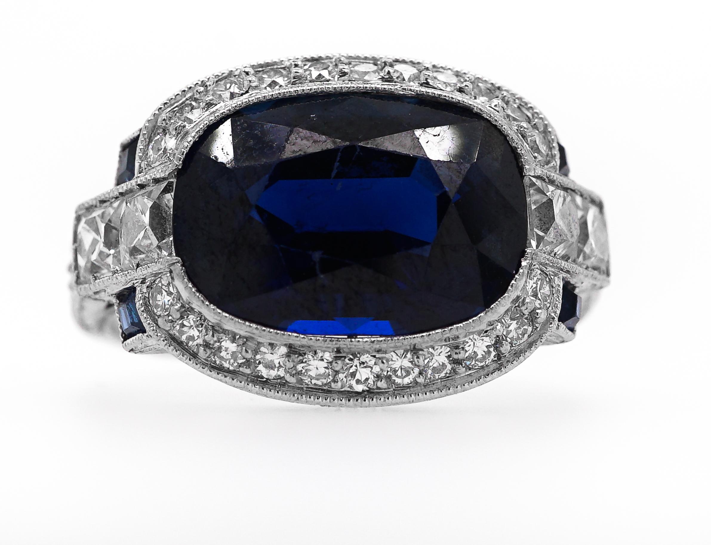 This item features one centered cushion-shaped sapphire approximately 3.75 cts., flanked by four French-cut diamonds approximately .30 ct and four small square-cut sapphires framed and flanked by 26 small round diamonds, circa 1930. Size 4 3/4. GIA