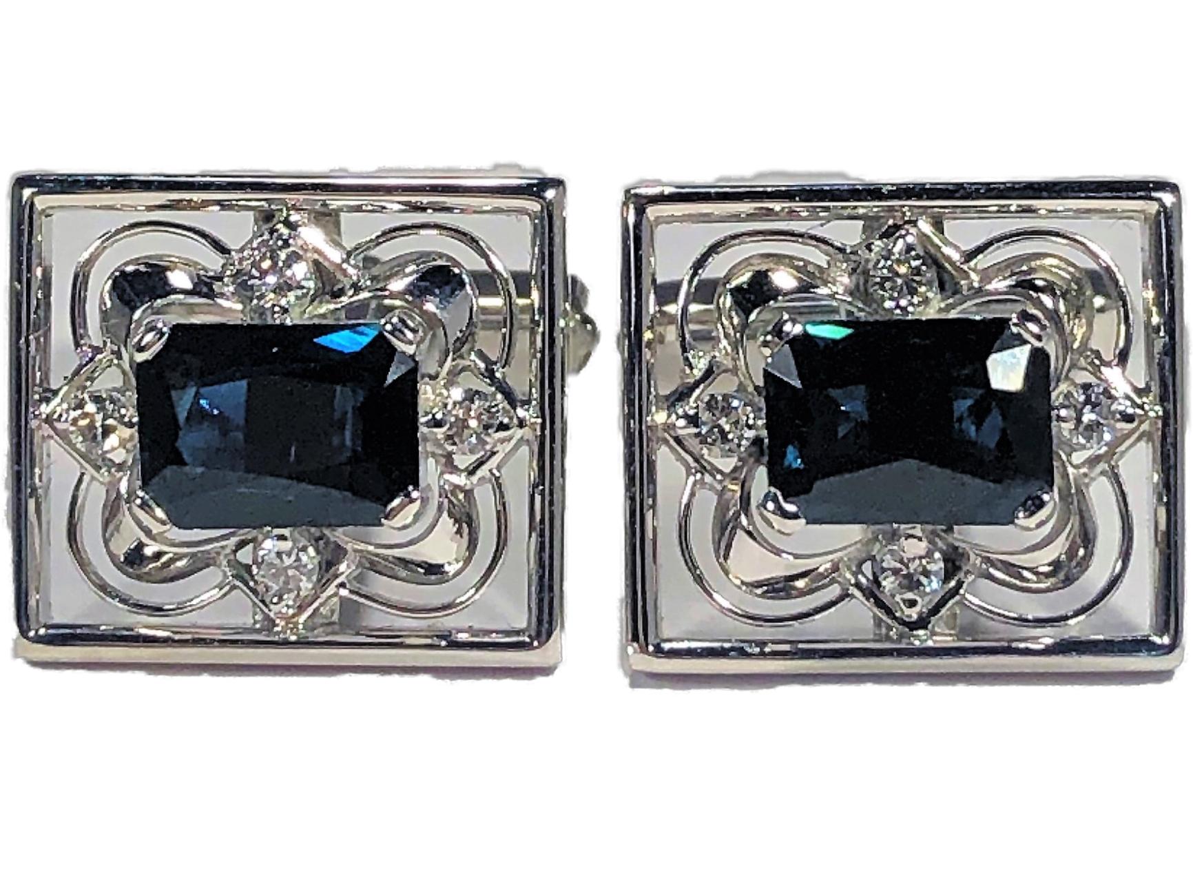 A pair of platinum cufflinks centered around an emerald cut sapphire, with round brilliant cut diamonds at the north, south, east, and west of the sapphire. Borrowing inspiration from both the Edwardian and Art Deco periods, they feature a geometric