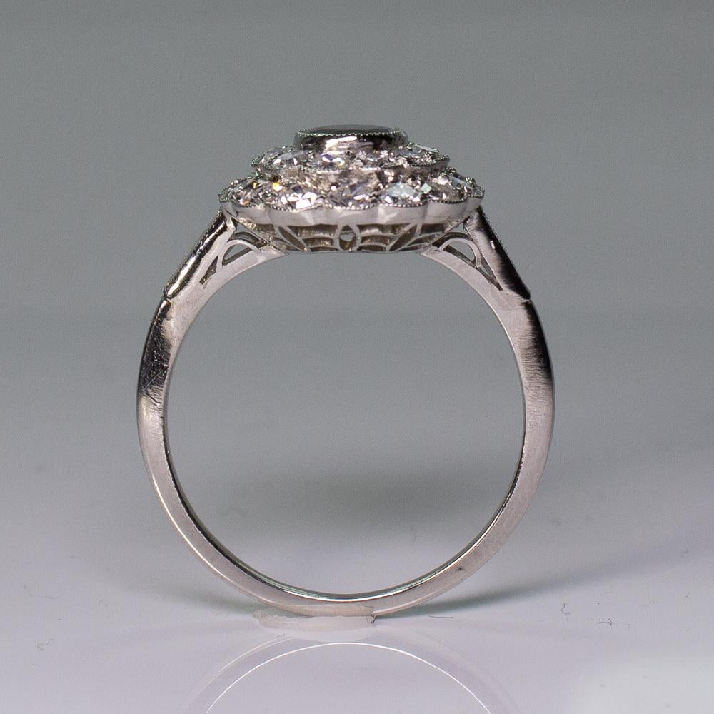 Anello con zaffiro e diamante aureolato in platino in stile Art Deco. In mostra uno zaffiro blu ovale taglio brillante di alta qualità del peso di circa 0,76 carati. Intervallati da 30 diamanti a taglio singolo e due a forma di baguette affusolata