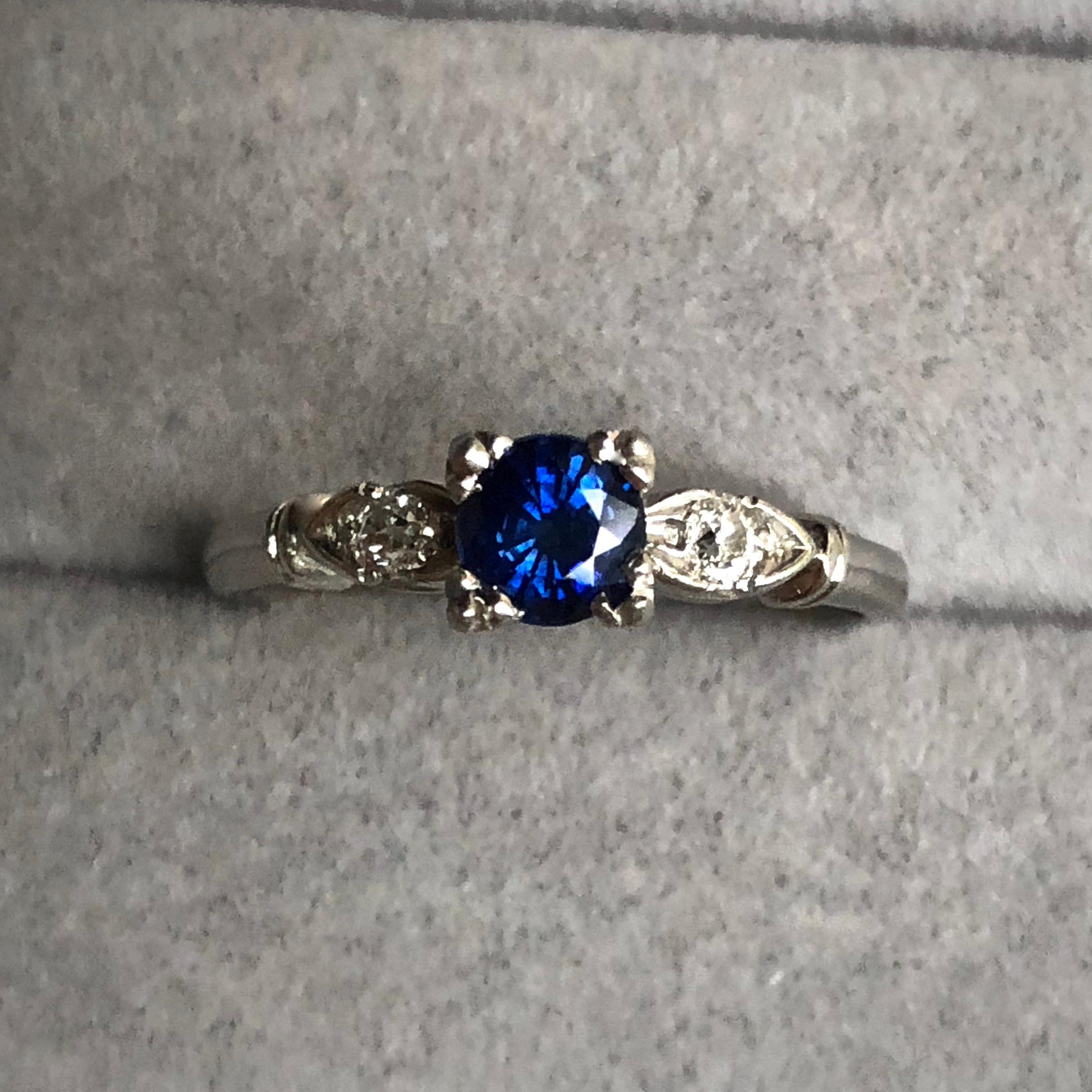 This is a lovely Vintage Art Deco royal blue Sapphire diamond Platinum Engagement Ring. It has a great design and holds 0.50ct royal blue sapphire round cut in the center and two approximate .05ct (each) old cut diamonds.  The size 7, ring weighs 3