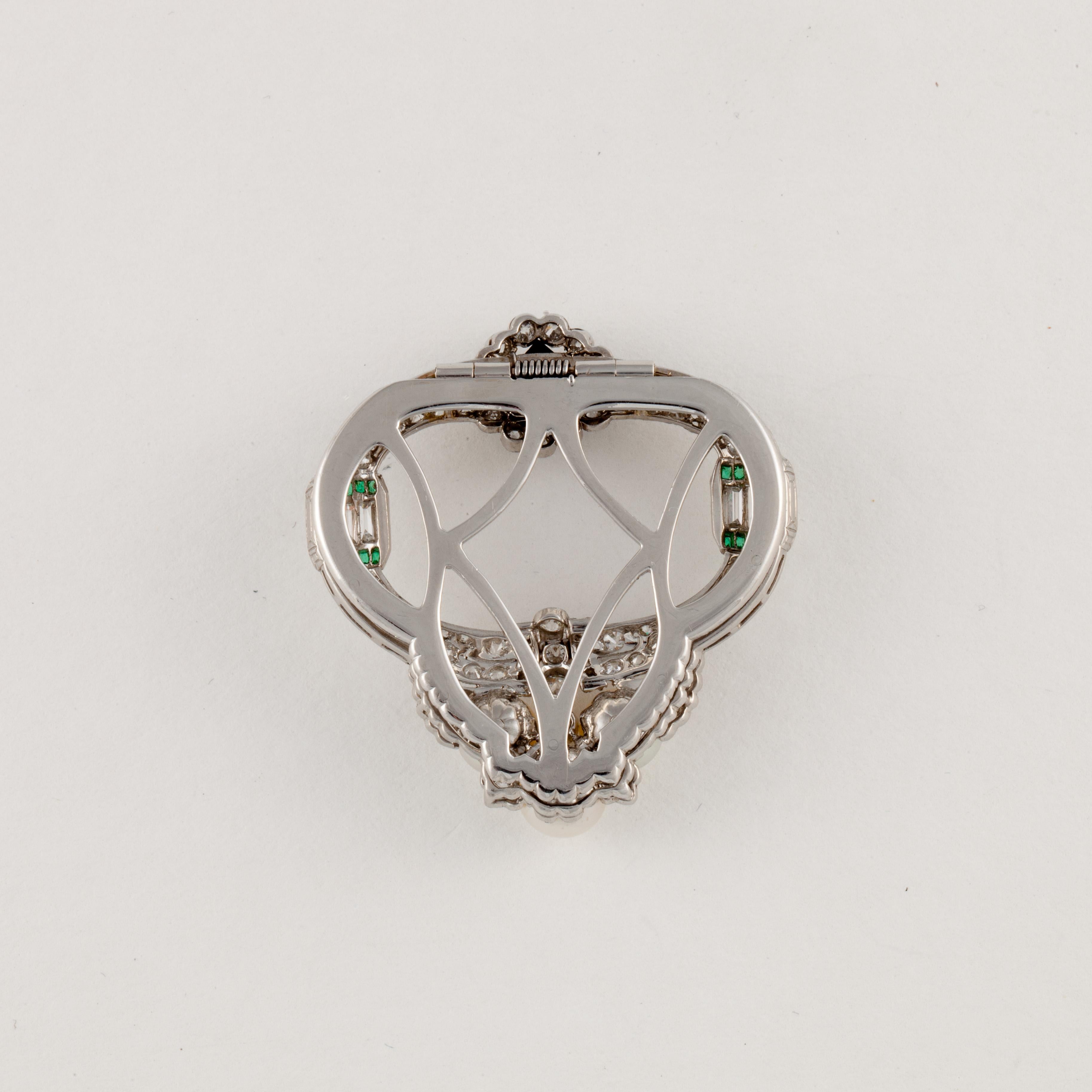 Platinum brooch featuring diamonds, onyx, cultured pearls and emeralds.  There are 3.35 carats of diamonds;  H-J color and VVS2-I1 clarity.  In addition, there are 0.22 carats of emeralds, the onyx measures 6.0mm and the three pearls are 6.5-7.0mm. 