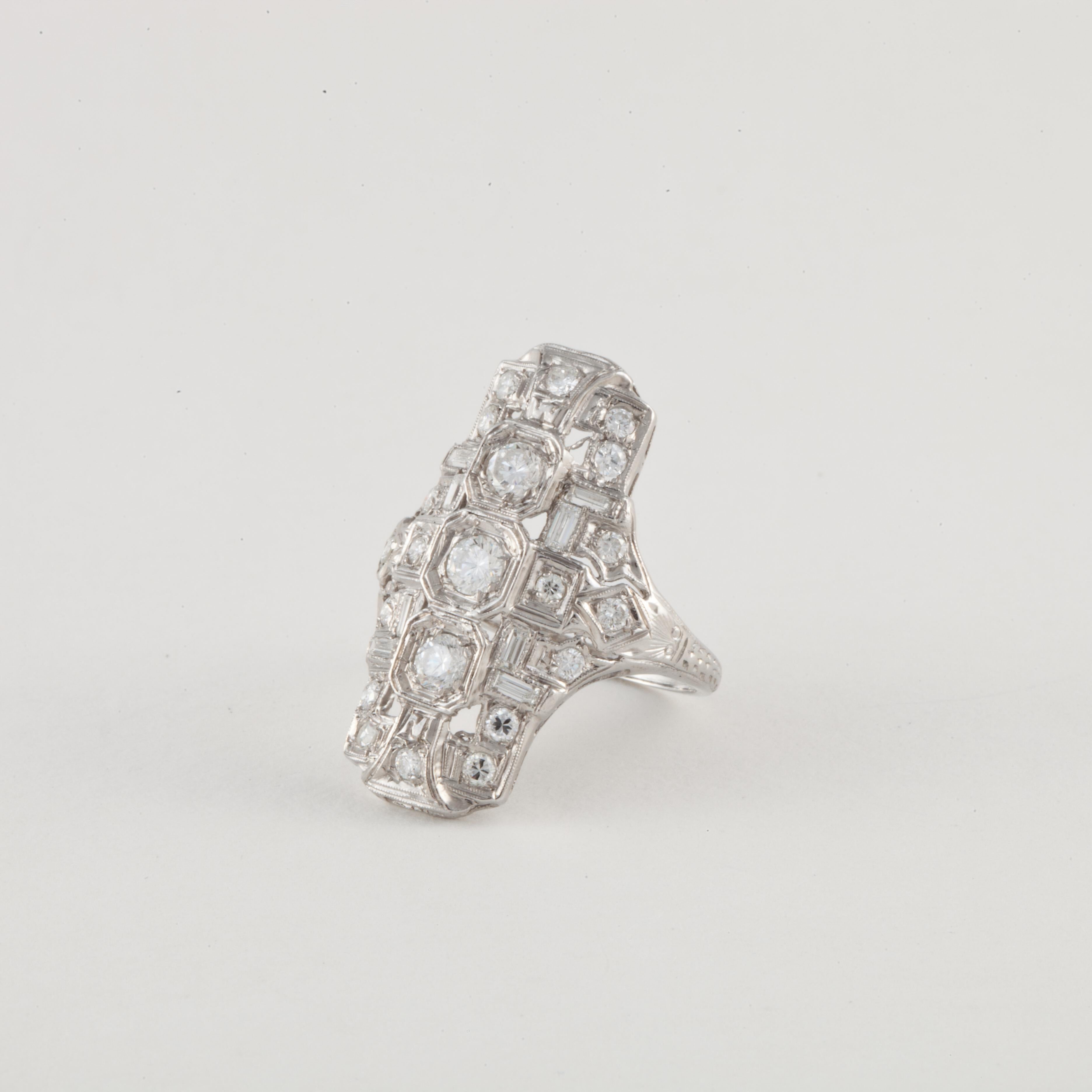 Art Deco ring crafted in platinum with diamonds.  There are a total of twenty-nine transitional round brilliant-cut and baguette diamonds weighing 1.05 carats; G-I color and VS1-SI1 clarity.  Ring measures 1 1/16 inches long and 3/4 inches wide. 