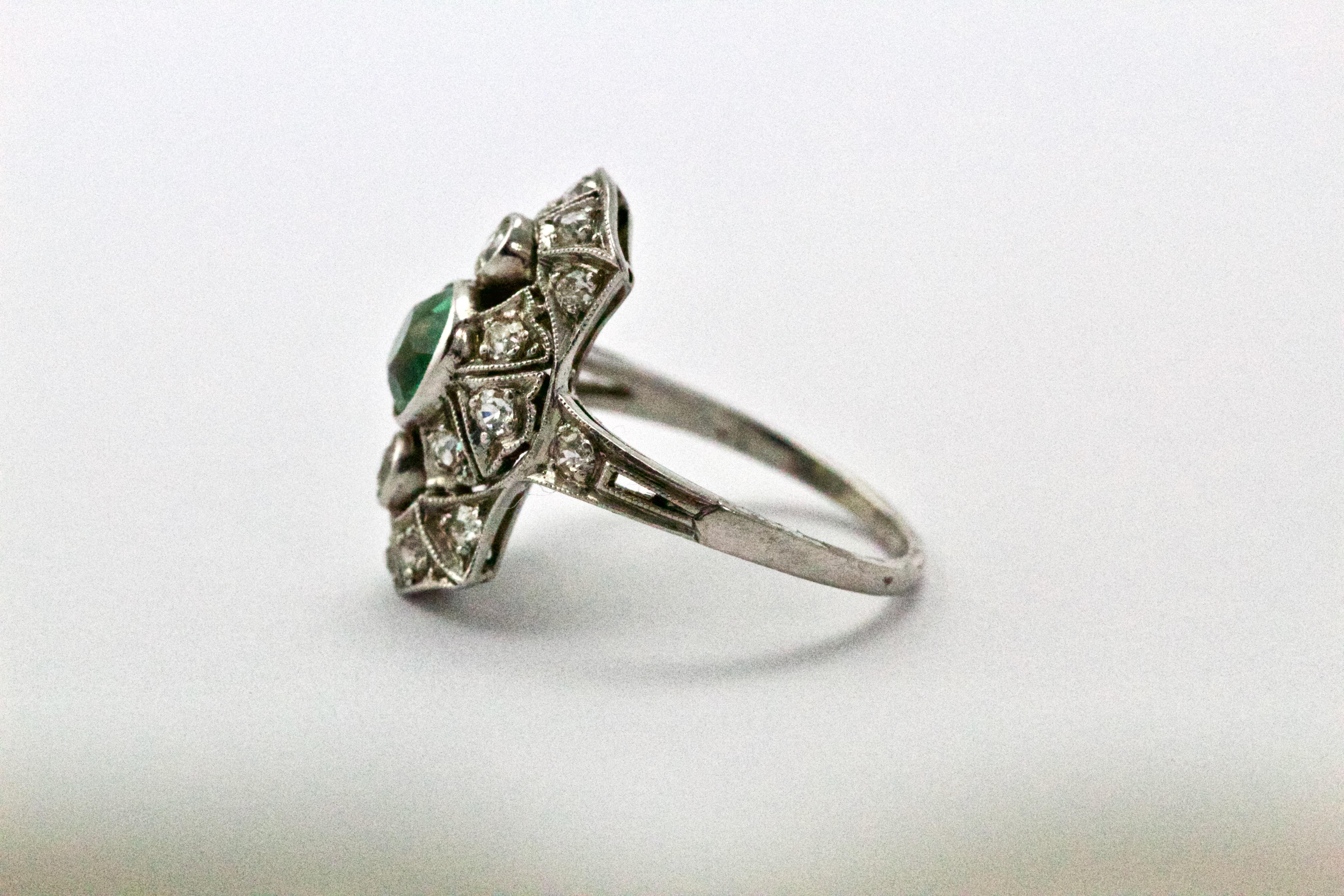 This wonderful panel ring features an enticing bright green old European cut emerald of approximately 50 points, centred in a pierced panel, with diamonds throughout. modelled in platinum throughout the millegrain edging and pierced, decorated