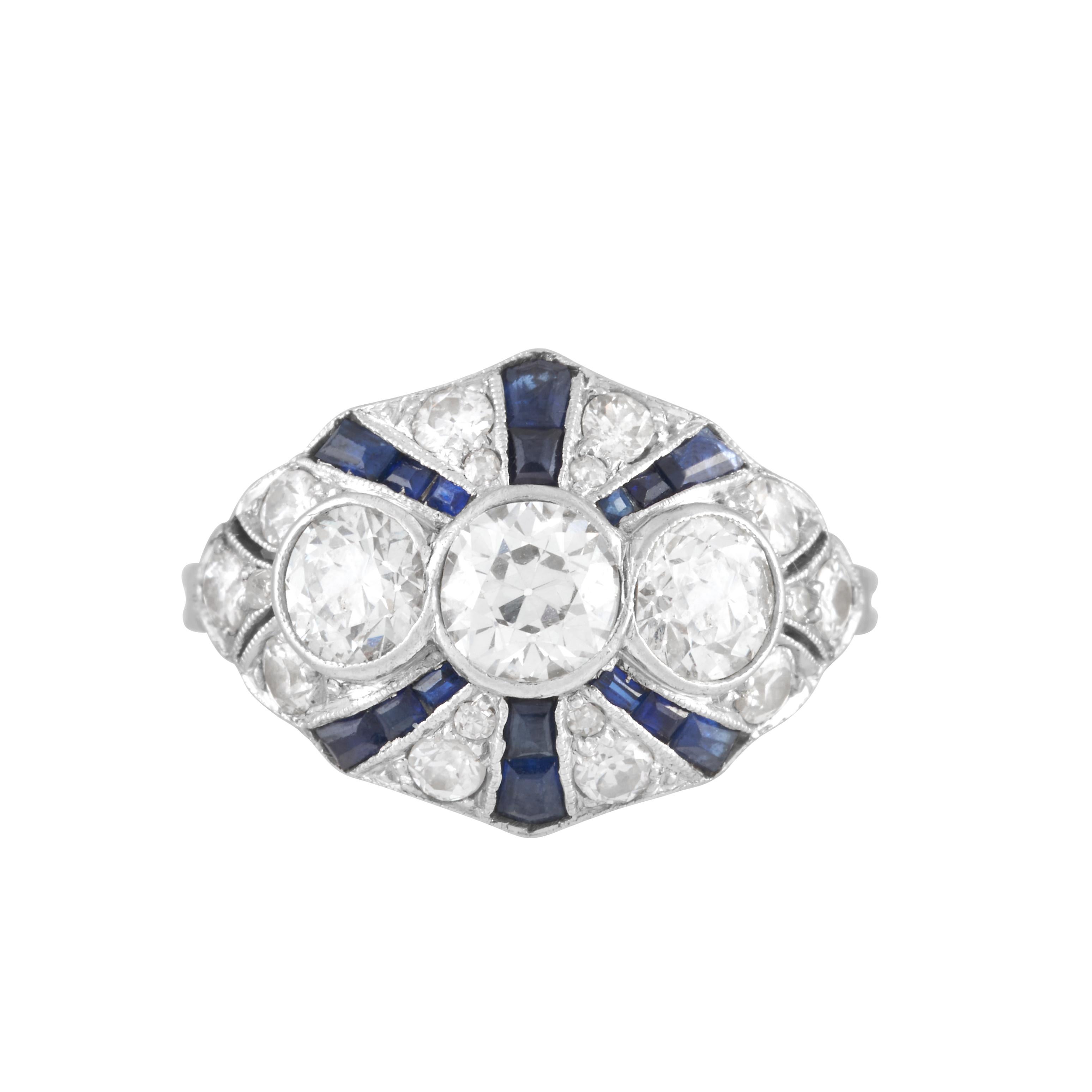 Art Deco ring with three bezel set Old European cut diamonds and radiating rows of synthetic sapphires set in platinum.
 
The center diamond of this ring weighs approximately 0.55 carat with J color and VS2 clarity, the two side diamonds total