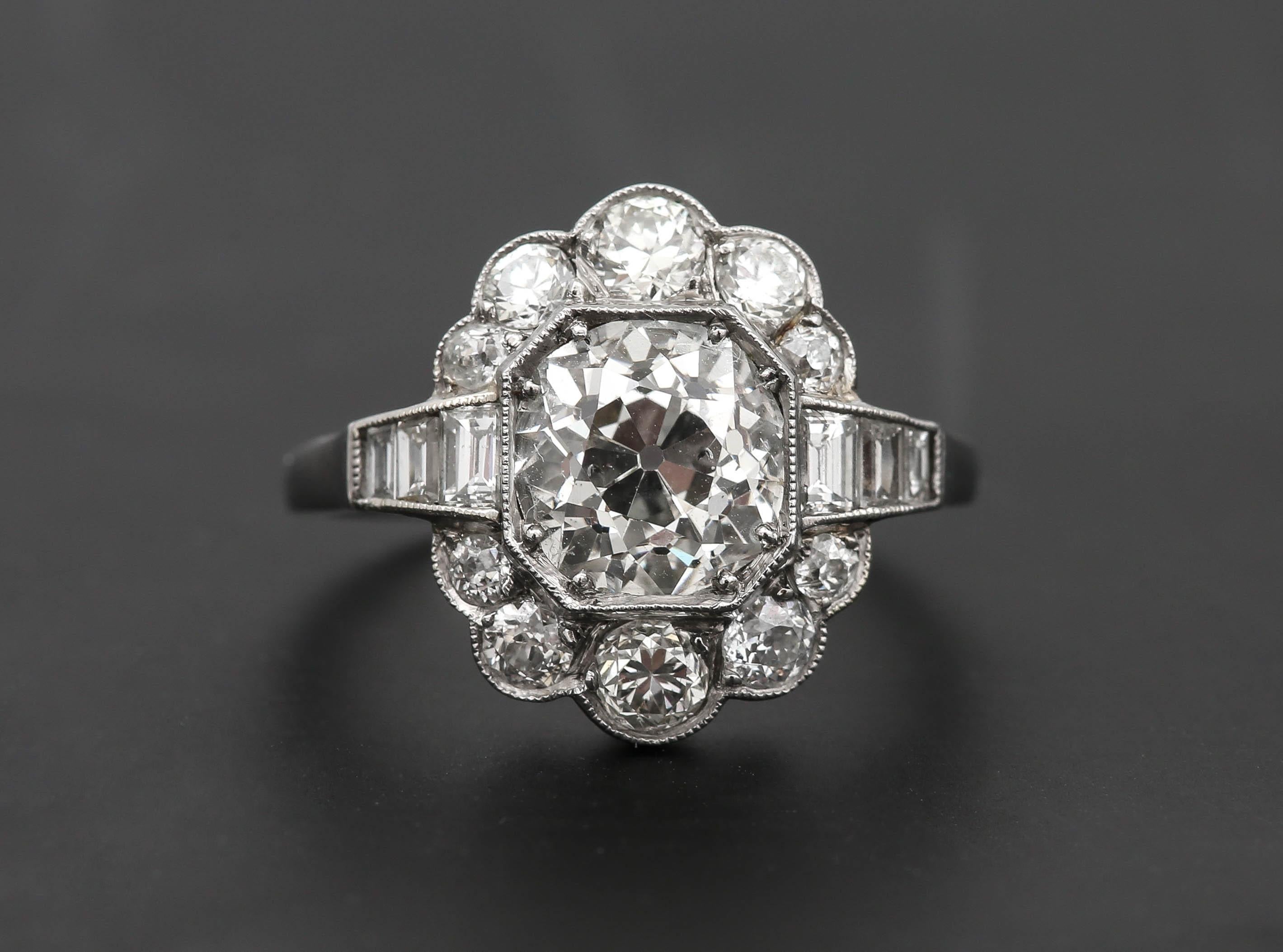 A fabulous Art Deco Old Mine Cut diamond cluster ring that has an estimated 1.75ct center stone in a millegrain octagonal setting. With flanking baguette shoulders 0.32ct to the solitaire diamond, enhancing this antique Art Deco ring. Furthermore,