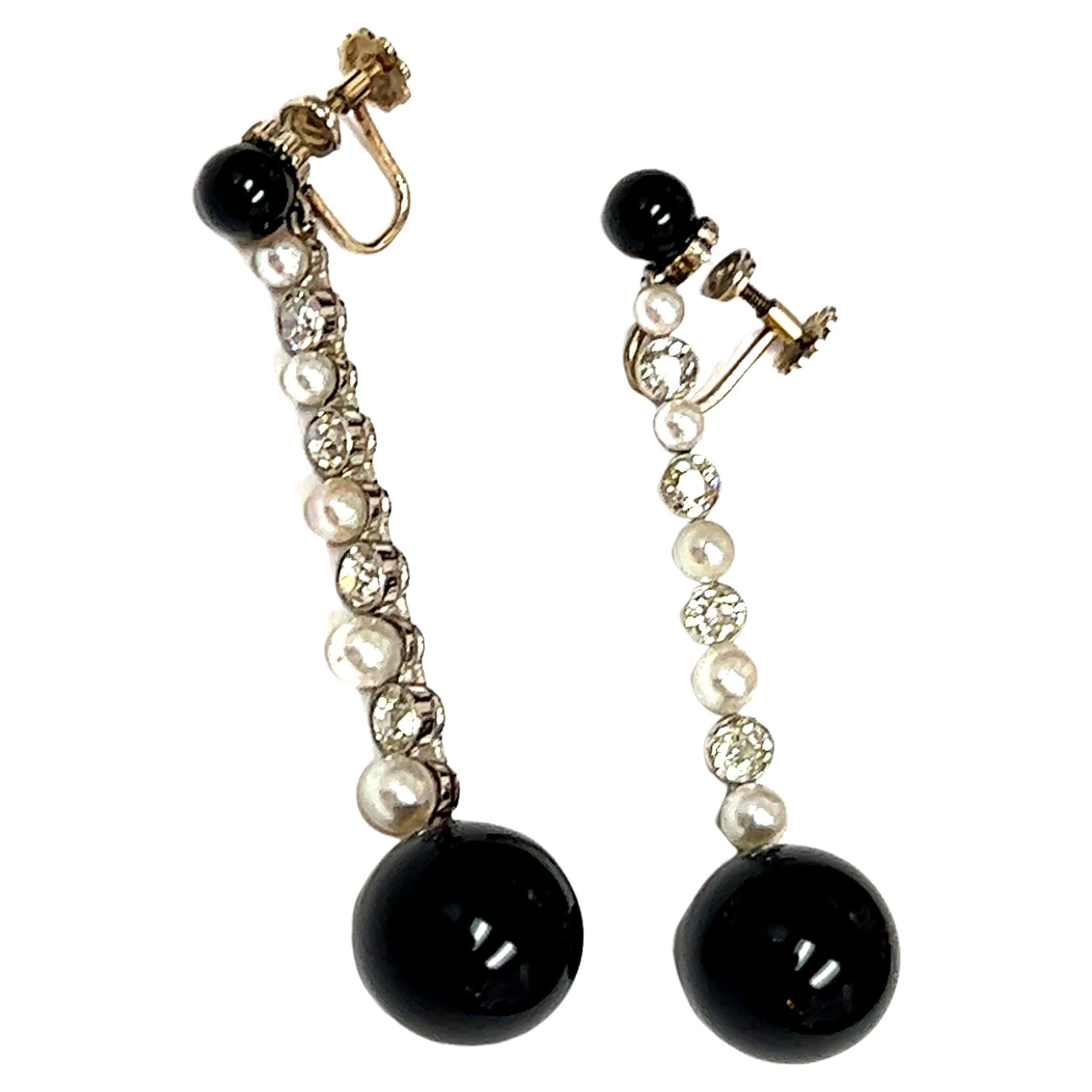 A stunning pair of Platinum Art Deco Onyx, Pearl, and Diamond Earrings, a true embodiment of the timeless elegance and geometric precision characteristic of the Art Deco era. The earrings feature round onyx beads that gracefully dangle, creating a