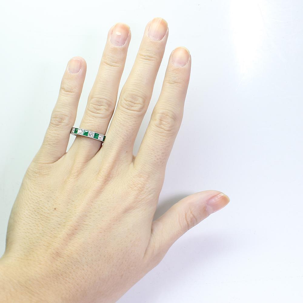 Platinum antique emerald and diamond eternity band ring. Showcasing 11 French cut fine quality natural emeralds and 11 Old European cut diamonds weighing a total of 0.85 carats. It is a finger size 7. The ring features hand engraving with a scroll