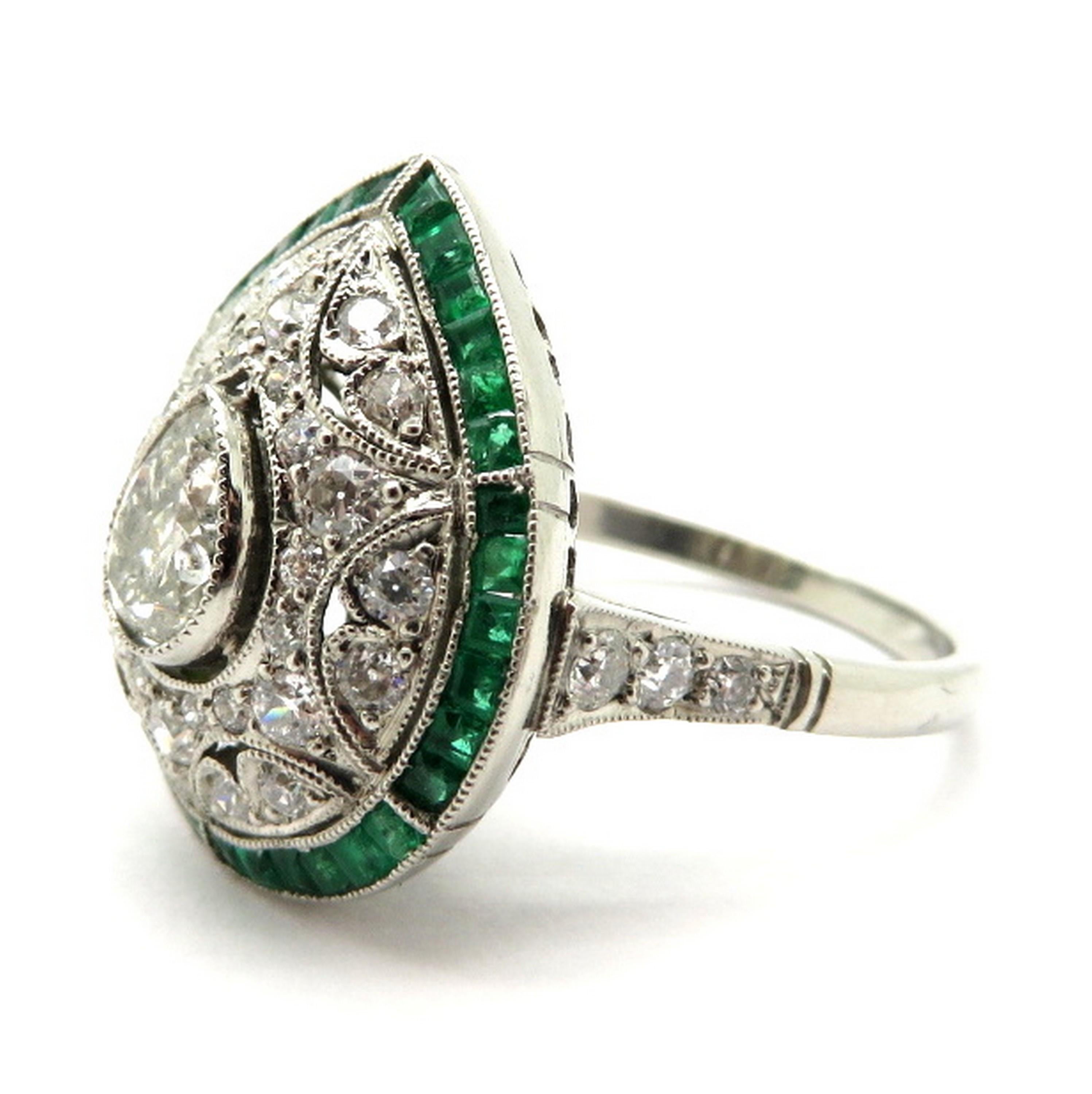 Platinum Art Deco style diamond and emerald engagement ring. Showcasing one pear brilliant cut diamond, milgrain bezel set, weighing approximately 0.58 carats. Diamond grading: color grade: I. Clarity grade: SI3. Accented with numerous Old European