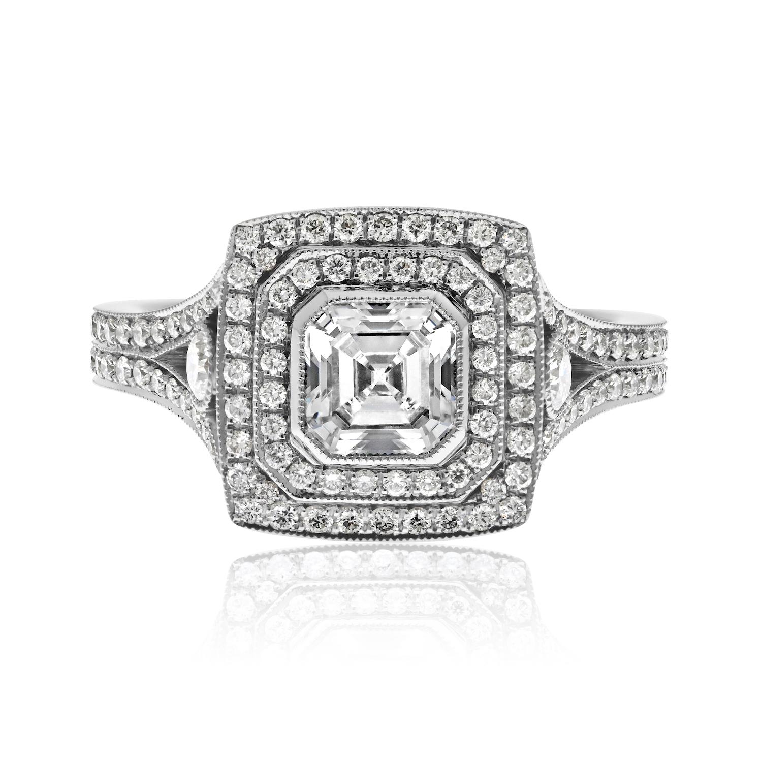 Der handgefertigte Ring zeigt einen prächtigen Diamanten im Asscher-Schliff, der von einem doppelten Pave-Halo umgeben ist und elegant auf einem geteilten Schaft sitzt. Schauen wir uns die Details an, die diesen Ring zu einem wahren Schmuckstück