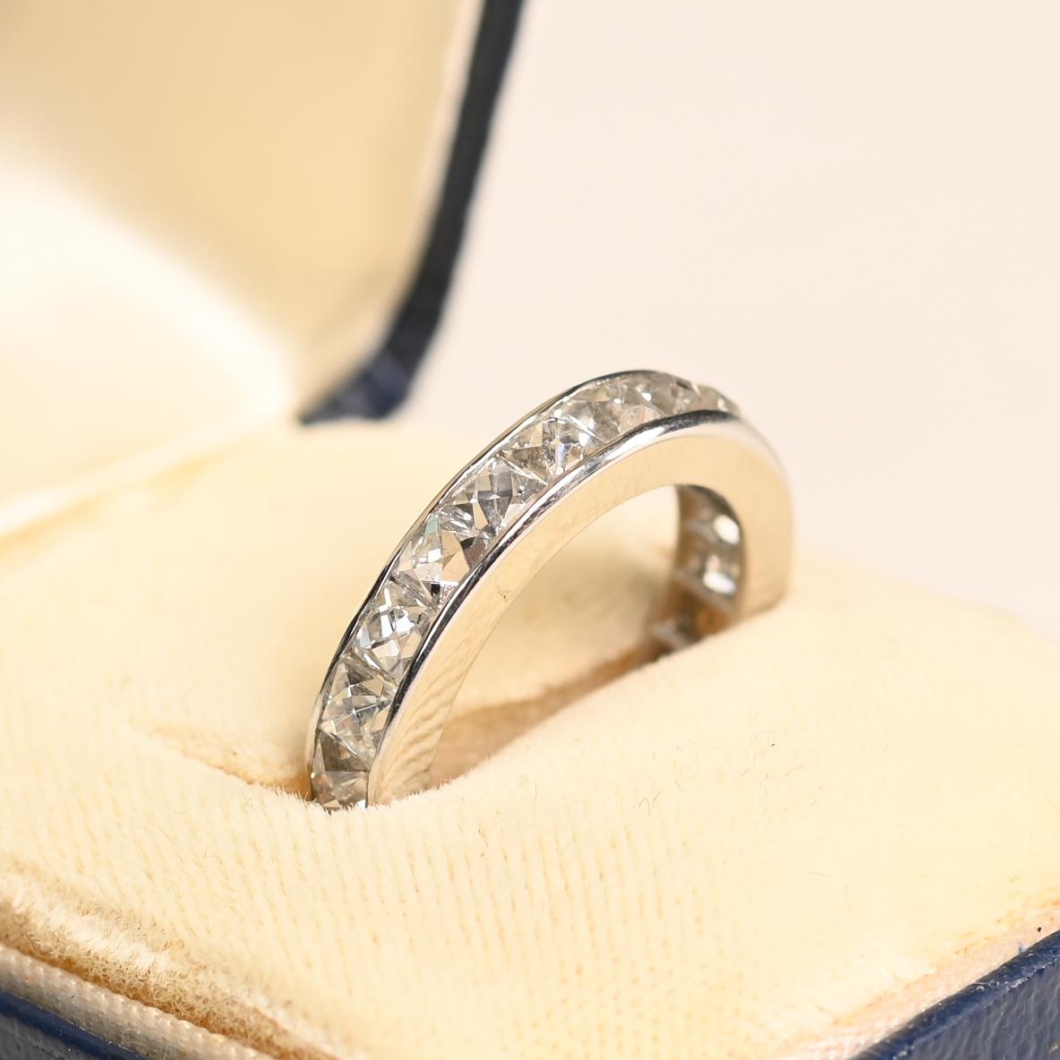 Dieses exquisite Ewigkeitsband aus Platin und Diamanten zeigt einen nahtlosen Kreis aus antiken Diamanten im französischen Schliff, die für ihre einzigartige Facettierung und zeitlose Eleganz bekannt sind. Die Diamanten mit einem Gesamtgewicht von