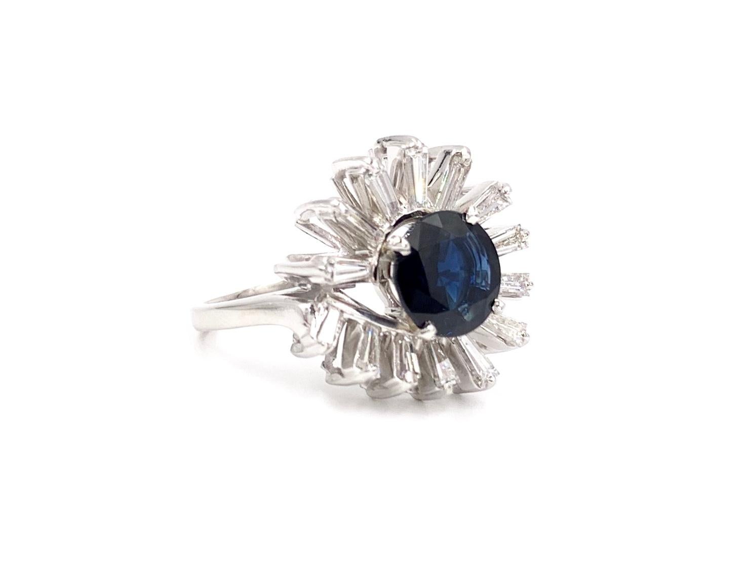Fashionable and modern designed platinum baguette diamond and 2.63 carat round deep blue sapphire ring. 14 vibrant baguette diamonds have an approximate total weight of 1.25 carats with approximately F color, VS2 clarity. Round blue sapphire has