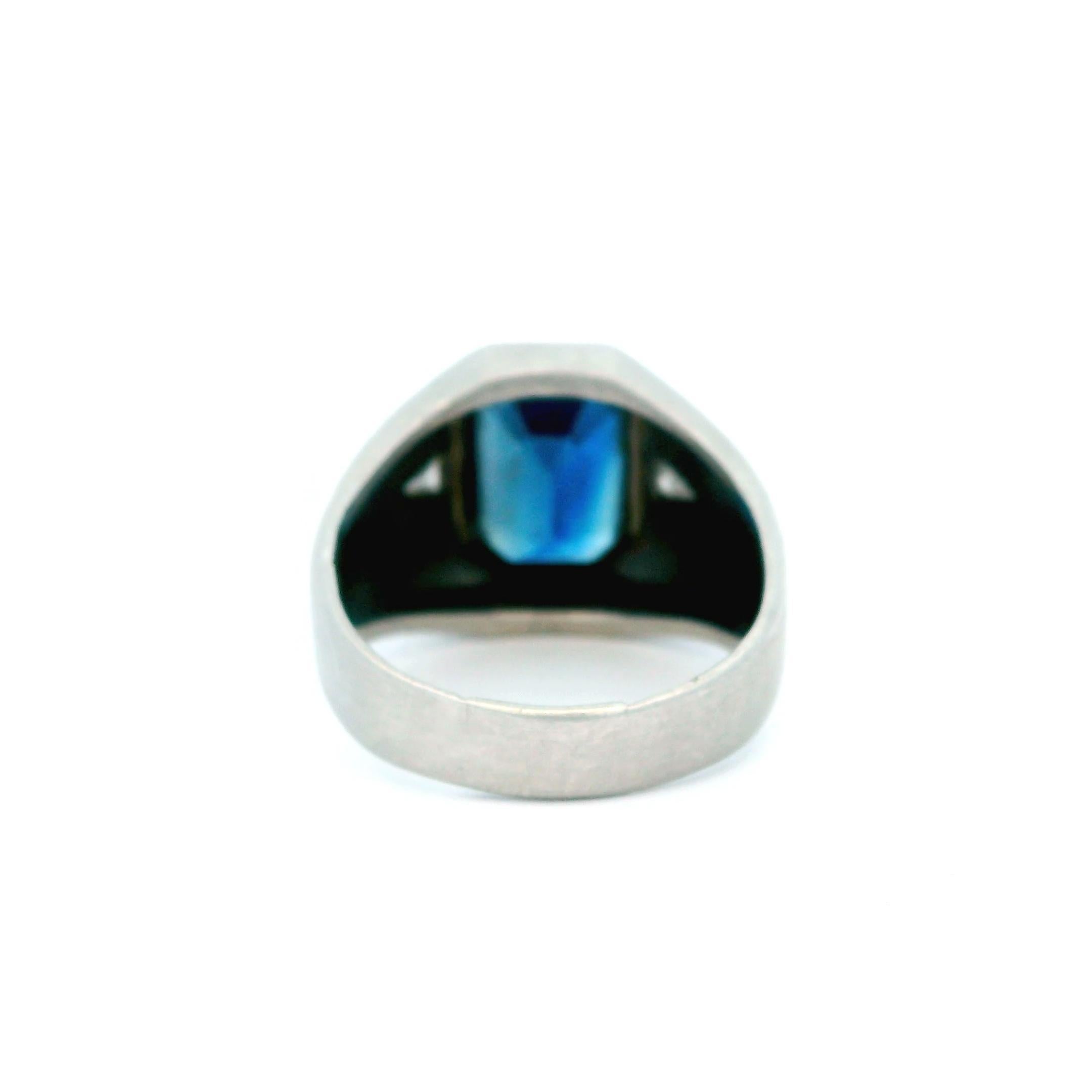 Elegant 21st Century Platinum Blue Sapphire and Diamond Ring. This striking ring is crafted in platinum, featuring a captivating emerald-cut blue sapphire at its center. Flanking the sapphire are two trilliant-cut white diamonds, adding a touch of
