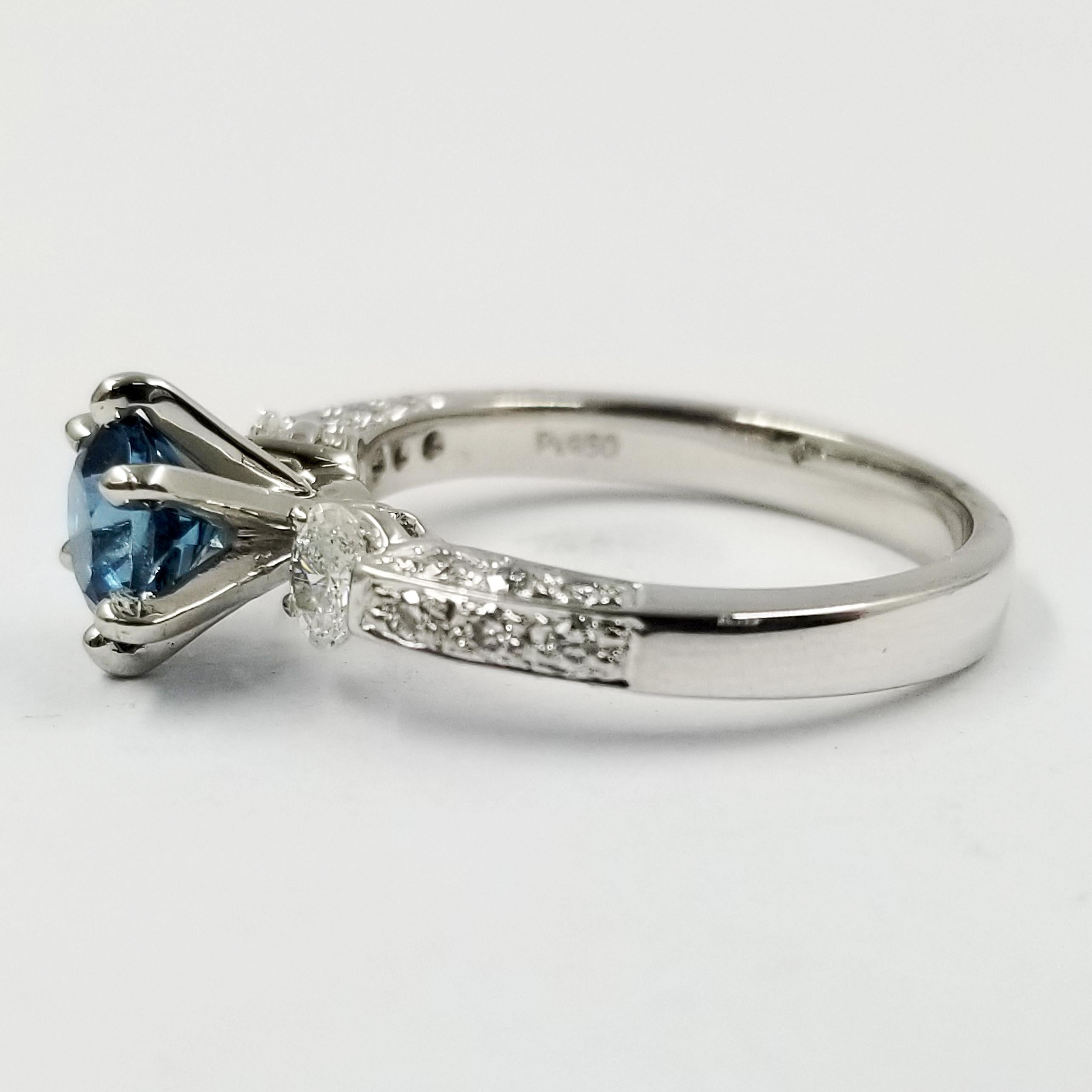 Platinum Ring Featuring a 1.02 Carat Bright Blue Topaz Center Stone in a 6 Prong Setting. The Mounting Also Contains 2 Oval and 18 Round Diamonds of VS Clarity & G Color Totaling 0.47 Carat Total Weight. Current Finger Size 7; Purchase Includes Free