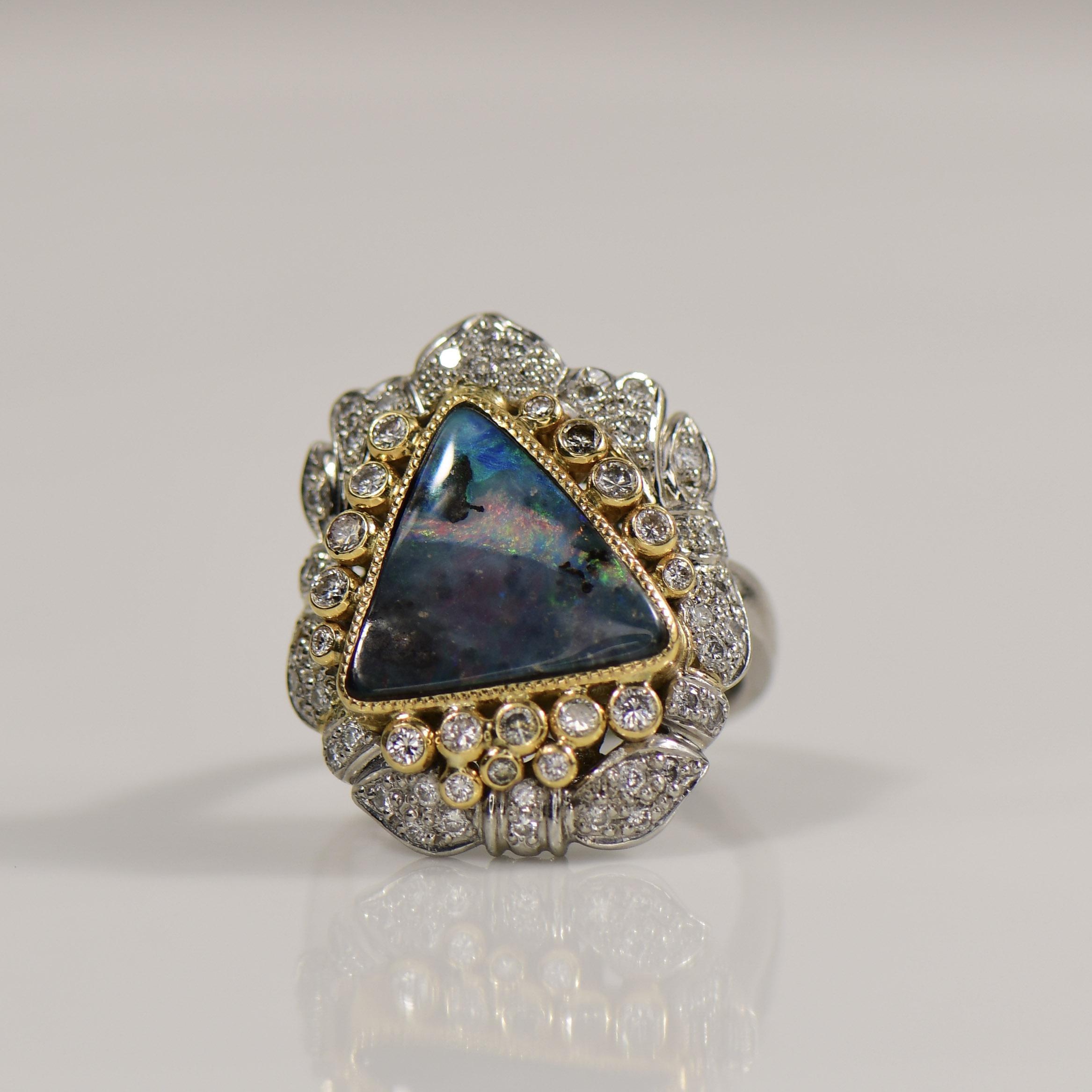 Behold the exquisite elegance of the Platinum Boulder Opal and Diamond Ring, a mesmerizing piece that seamlessly marries nature's beauty with meticulous craftsmanship. The center stage is graced by a captivating Boulder Opal, resplendent with its