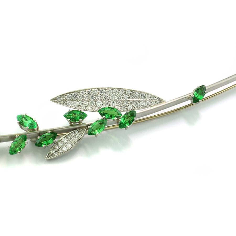 Auténtica pieza de coleccionista, este exquisito broche es una obra maestra del diseño de joyería fina, realizada a mano en el taller del aclamado orfebre Günter Krauss en Stuttgart. Inspirado en la elegante forma de una ramita en flor, el broche