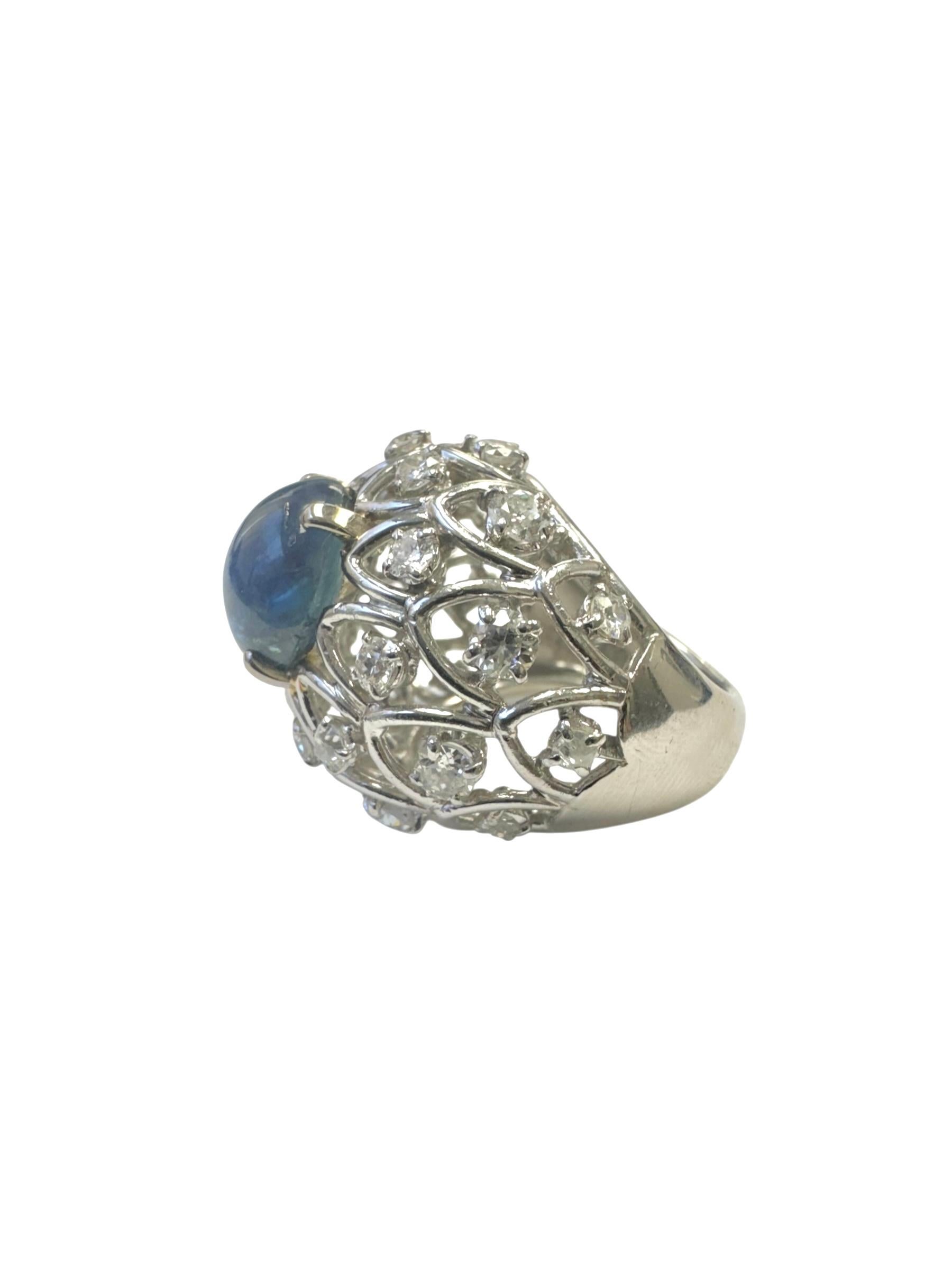 Un anello audace e lussuoso realizzato in platino, con al centro uno zaffiro cabochon da 9,00 carati. Lo zaffiro blu reale profondo è incastonato in un ornato disegno a cupola traforata, impreziosito da circa 2,60 carati di diamanti brillanti a