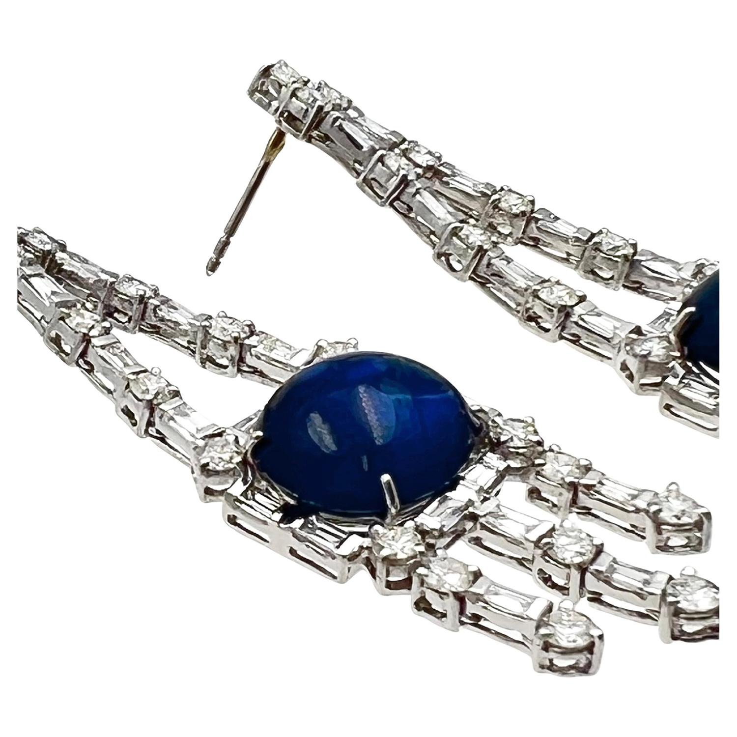 Saphirs cabochons sertis dans un chandelier en platine rehaussé de diamants ronds et baguettes.  Deux saphirs taillés en cabochon mesurent 13,12 x 11,31 x 4,84 mm (7,75 ncarat) et 12,86 x 11,19 x 5,87 mm (9,12 carat) pour un total estimé à 16,87