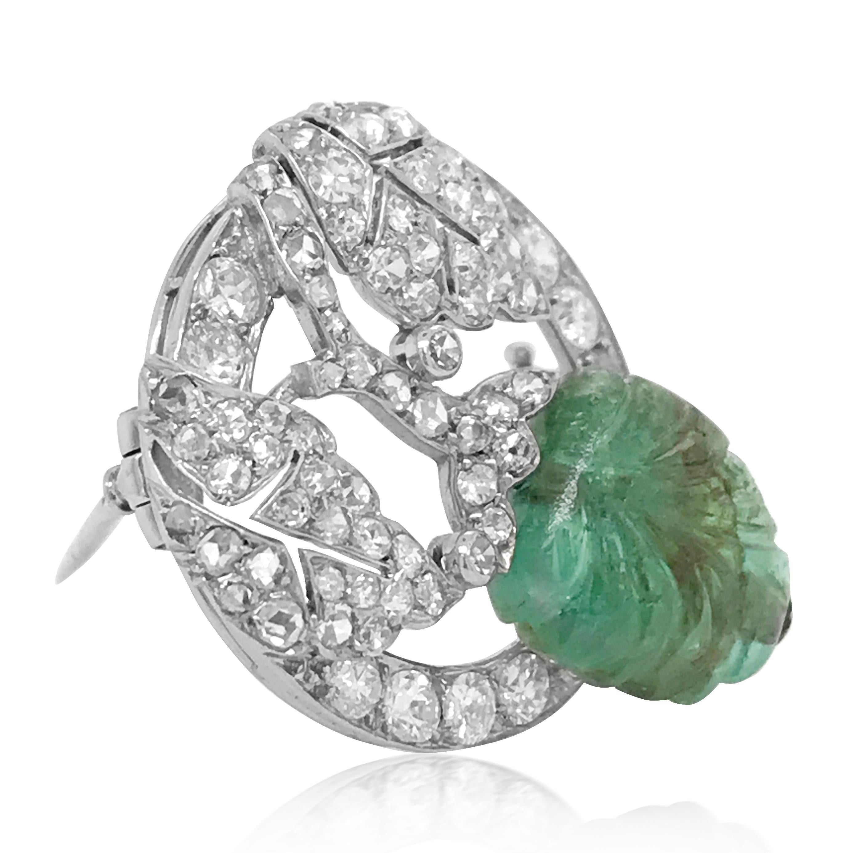 This stylized Marchak openwork leaf motif brooch is centered with one carved emerald leaf approximately 12.2 x 11.2 x 6.6 mm, set with transitional, single and rose-cut diamonds weighing cumulatively 1.0ct, several H-I-VS-SI, several chipped