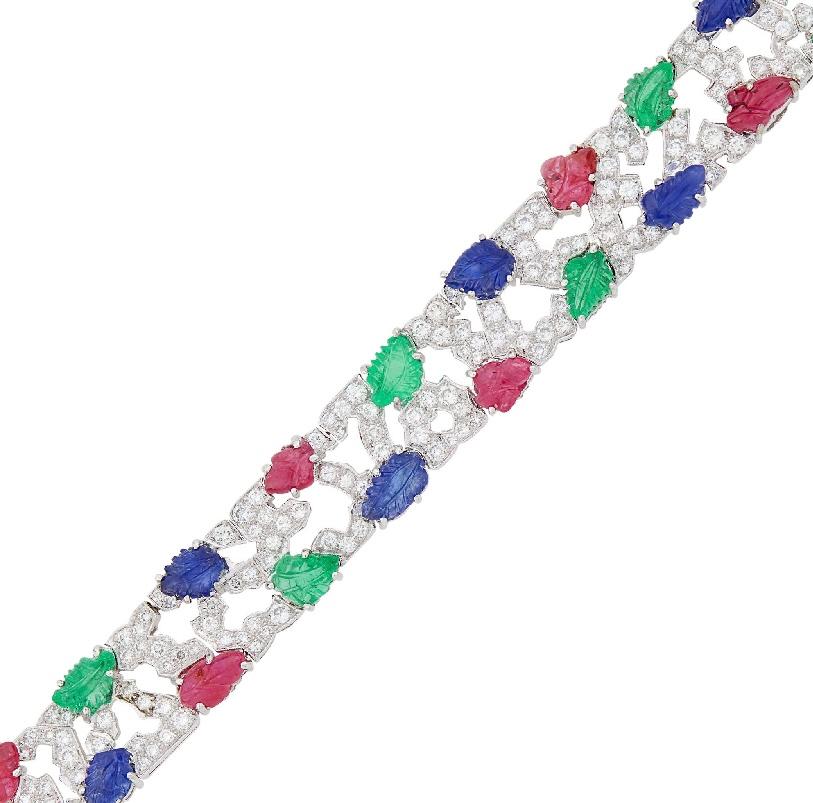 Platinum, Carved Colored Stone and Diamond Bracelet 20 carved ruby, sapphire and emerald leaves, 238 round and 2 baguette diamonds ap. 7.30 cts., Length 7
1/4 inches. Weight: 34.1 grams