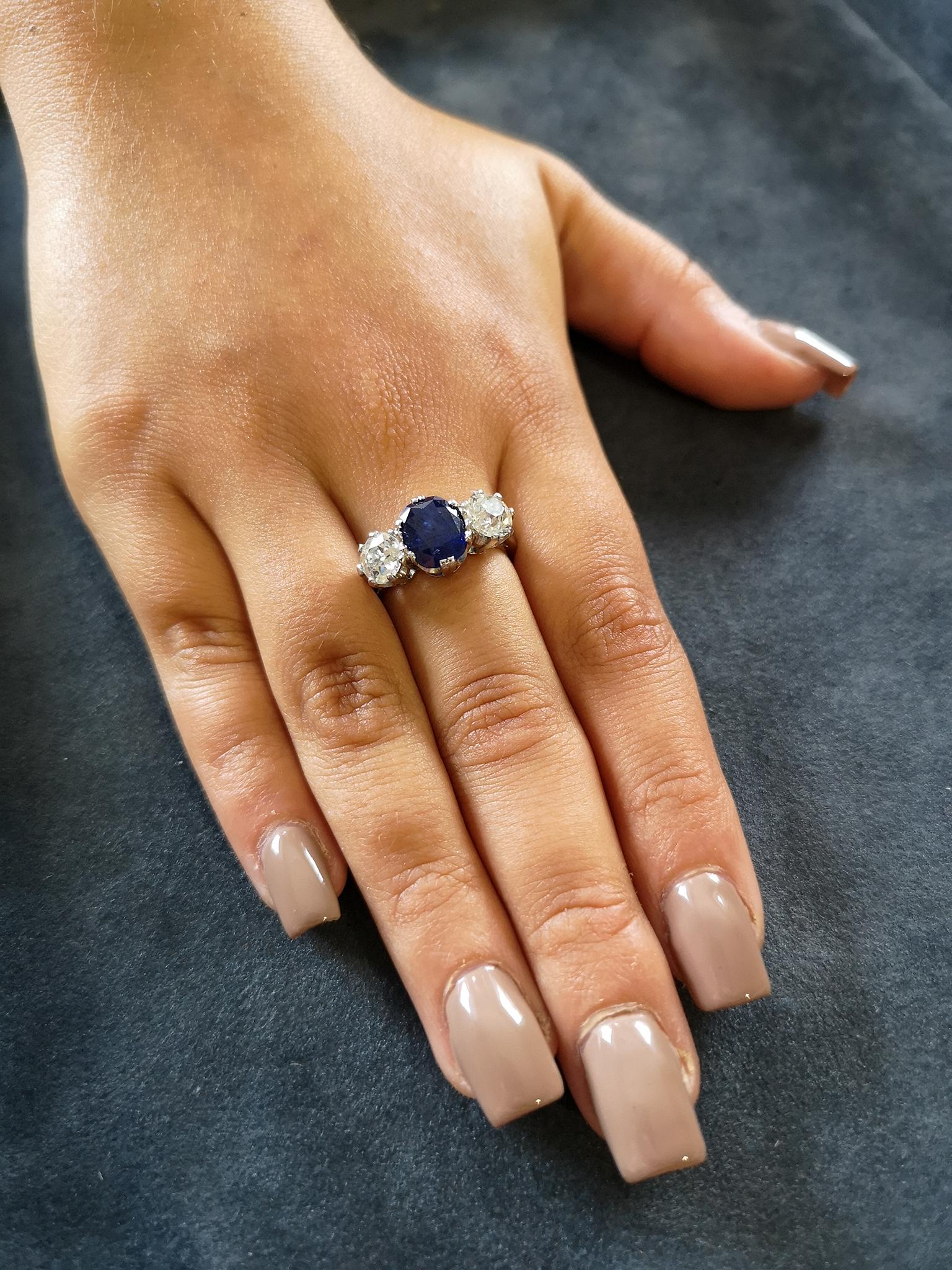  The 3.75 carat natural, untreated Burma sapphire of a gorgeous, deep, inky-blue colour mounted in platinum claws, flanked on each side by a single old-cut diamond, each of approximately 1.20 carats, H-I colour, SI clarity. Uniform, heavy polished