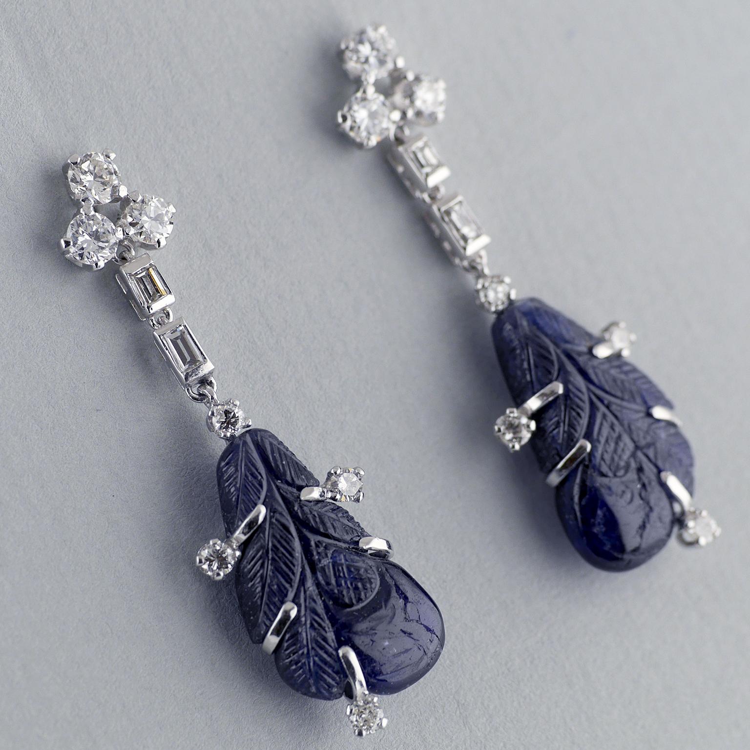 A pair of hand made white diamond and natural, untreated, carved sapphire drop earrings.

Two, well matched, certified, untreated, natural sapphires, carved into a leaf motif dropped from brilliant and baguette white diamonds and set in platinum and