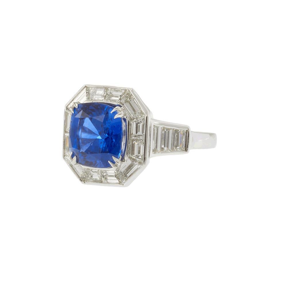 Ein auffälliger Platinring mit einem Ceylon-Saphir im Kissenschliff von 4,13 Karat, zertifiziert von AGL. Der leuchtend blaue Mittelstein wird von 2,10 Karat Diamanten im modifizierten Baguetteschliff (G-VS) in einem eleganten achteckigen Halo